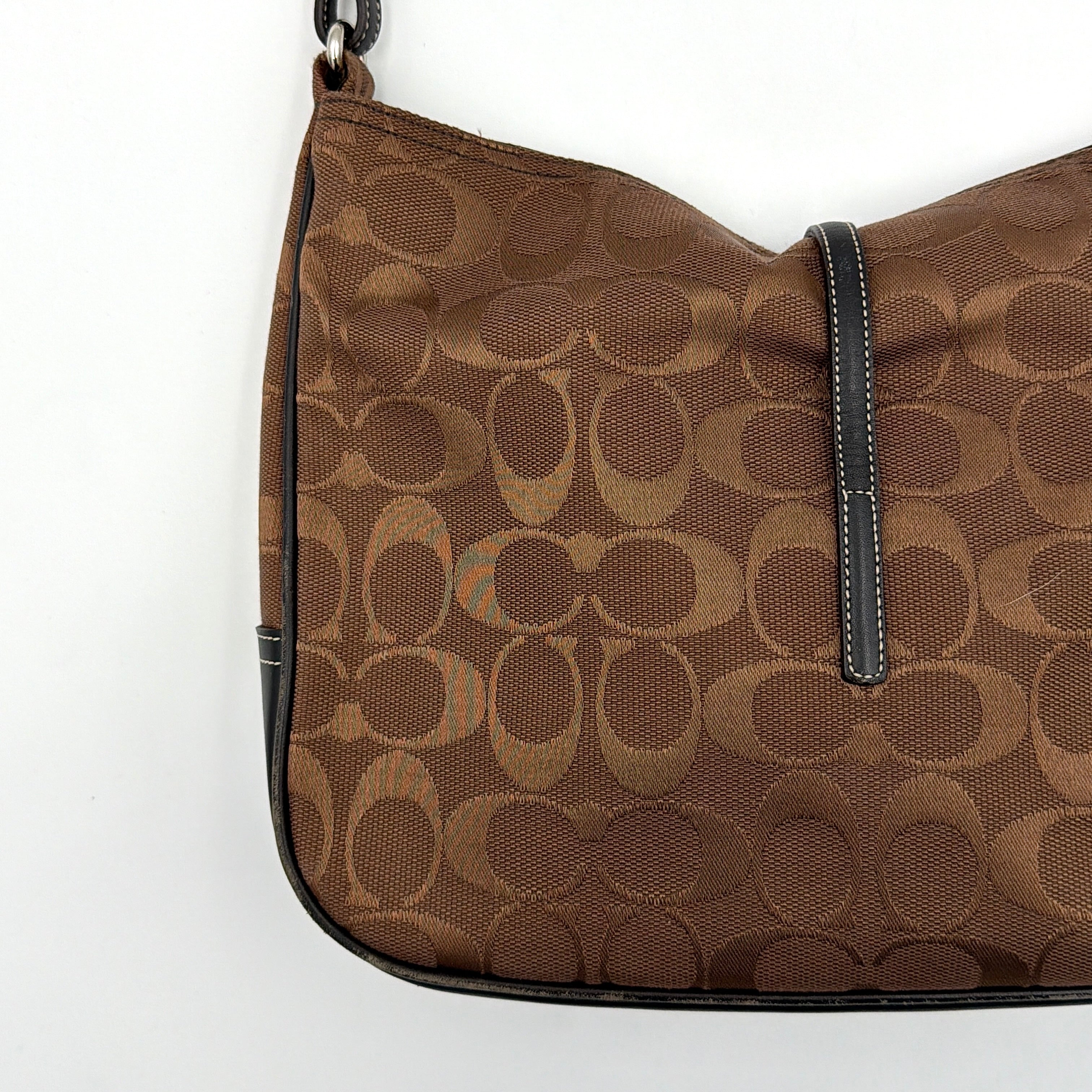 Coach Hobo Signature Clip canvas handbag in brown with black leather trim and silver hardware displayed against a plain background.
