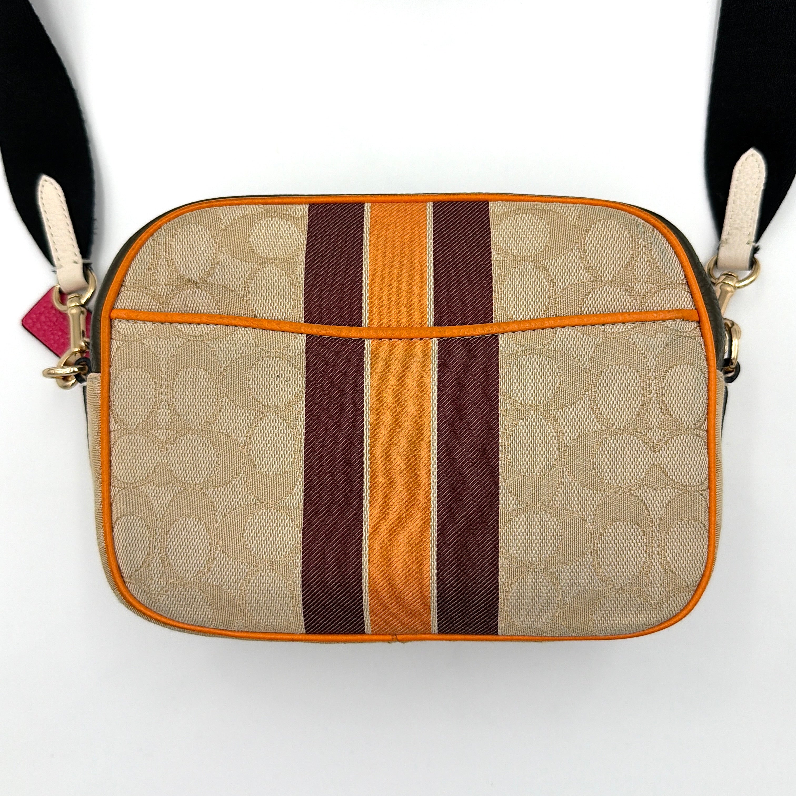 Coach Signature Dempsey Camera Bag in monogram canvas with bold pink logo patch, orange stripes, and wide black strap.