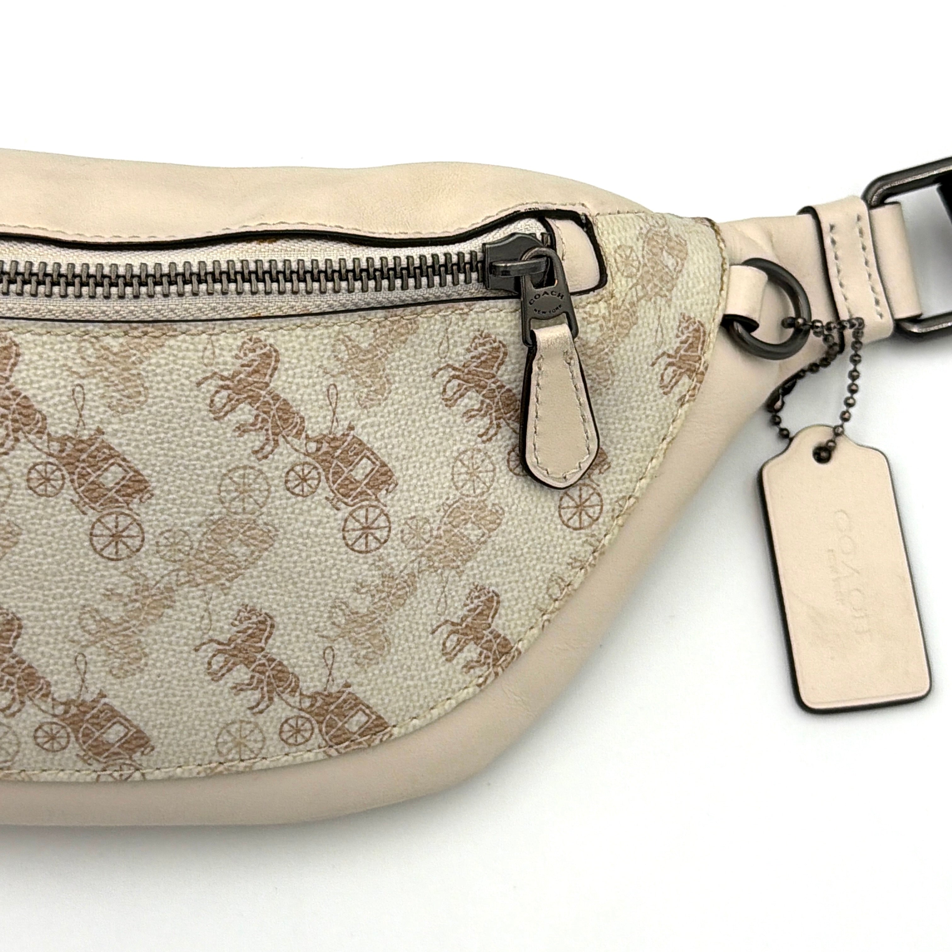 Coach Mini Warren belt bag in cream canvas with tan horse and carriage motif, leather trim, and black adjustable strap.