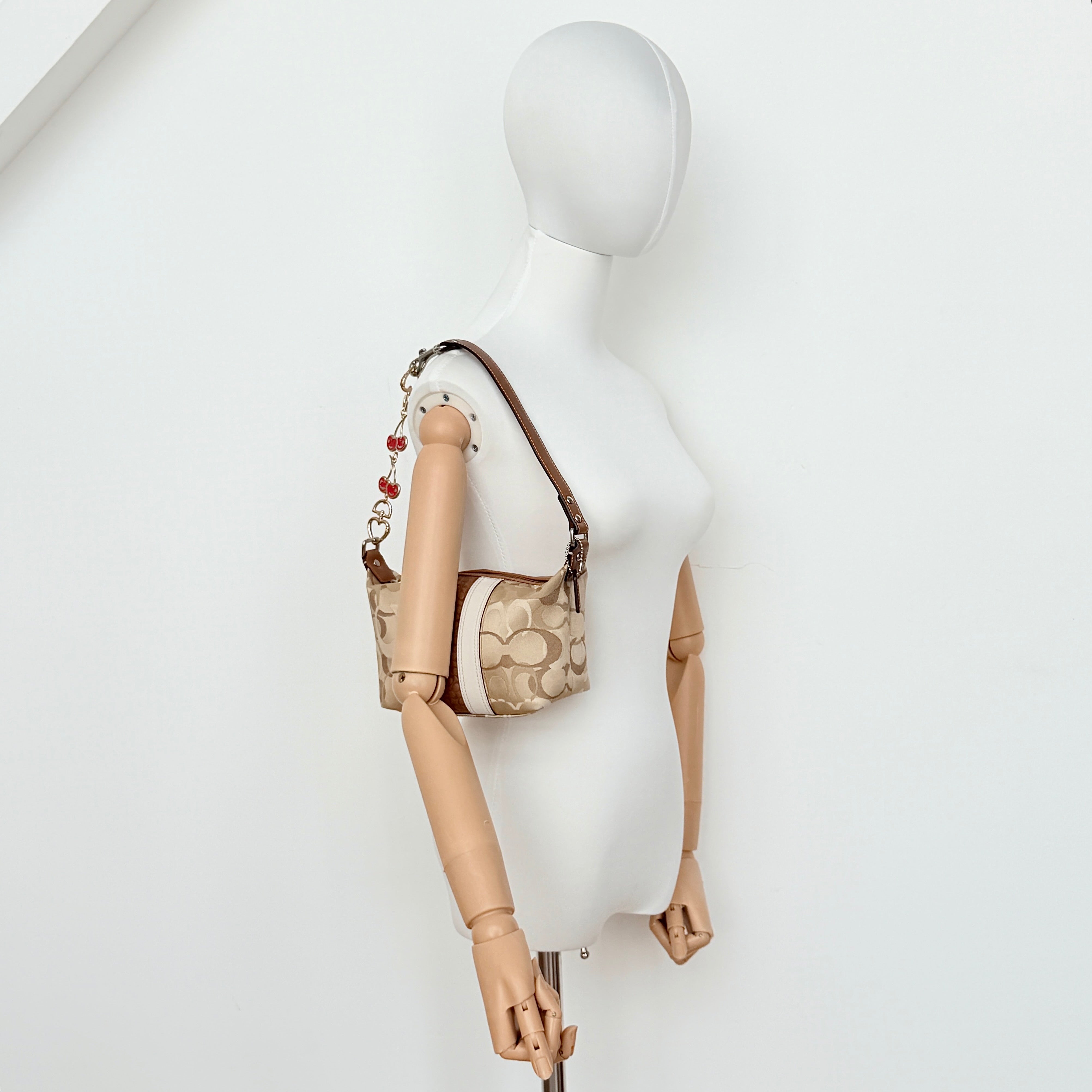 Coach Signature Stripe Mini Hobo Shoulder Bag in brown canvas with white and caramel stripes, featuring a brown leather strap and playful cherry charms.