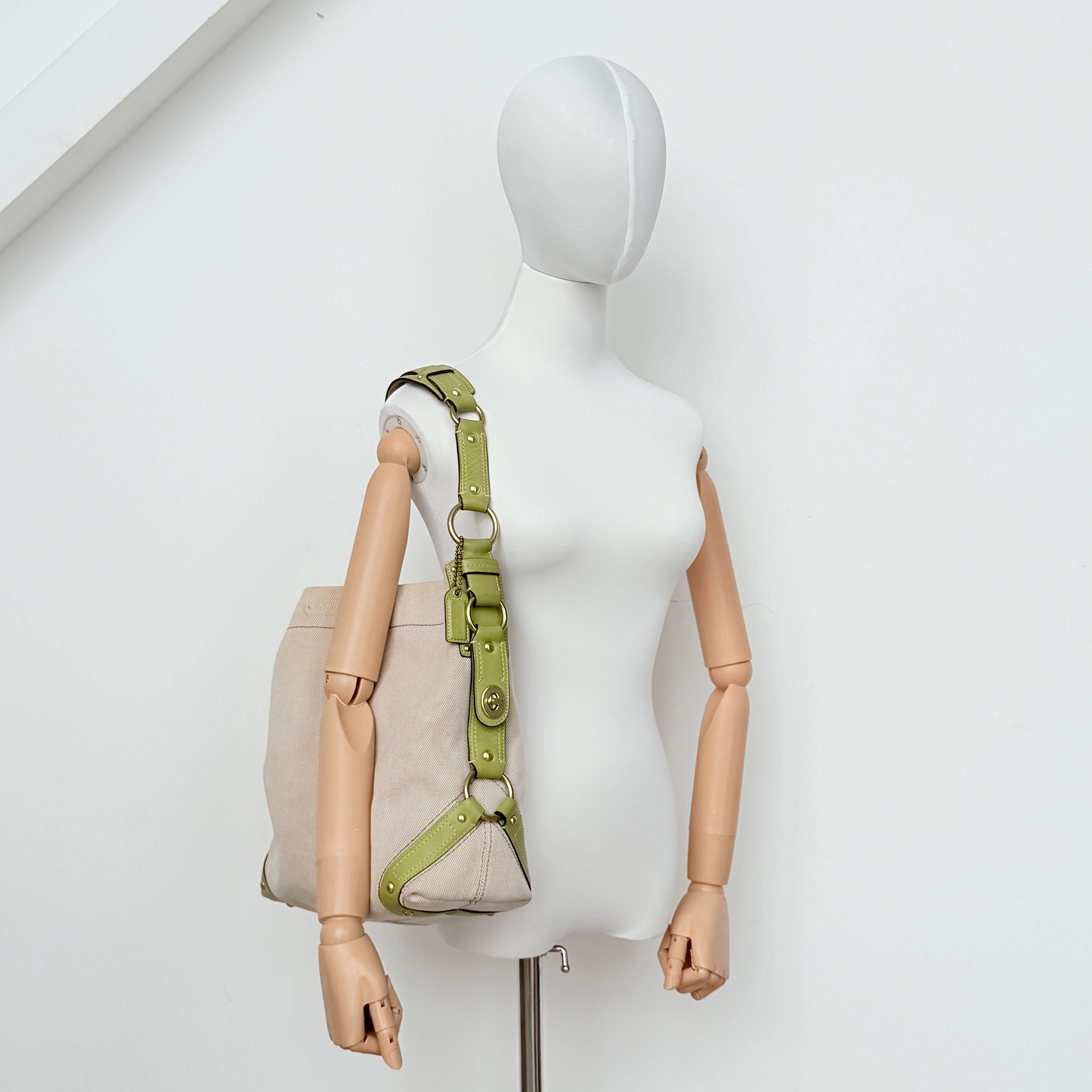 Coach Carly Hobo Shoulder Bag in beige canvas with green leather trim and gold hardware, shown on a white background.