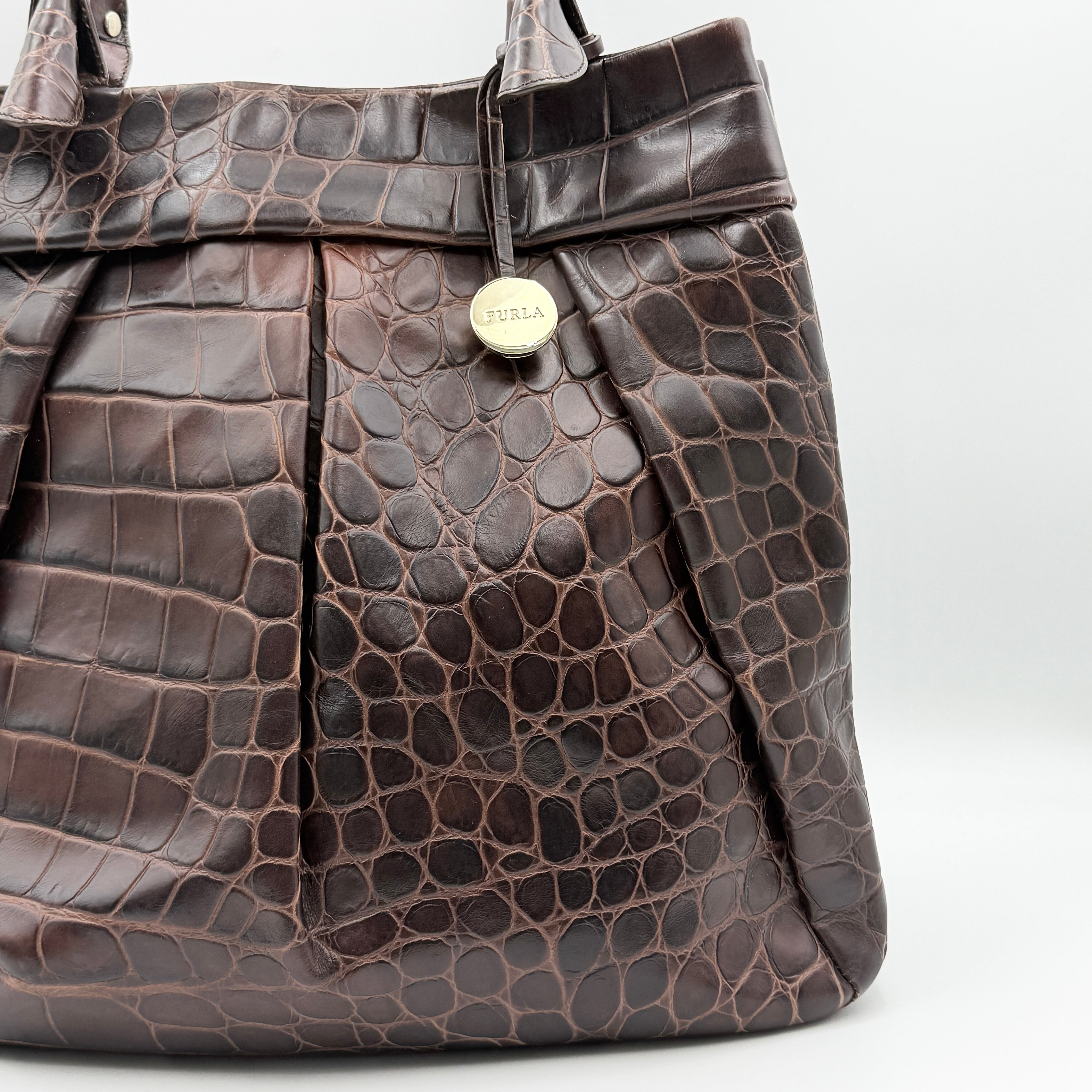 Furla dark brown croc-embossed leather tote bag with gold logo charm, structured silhouette, and double handles.