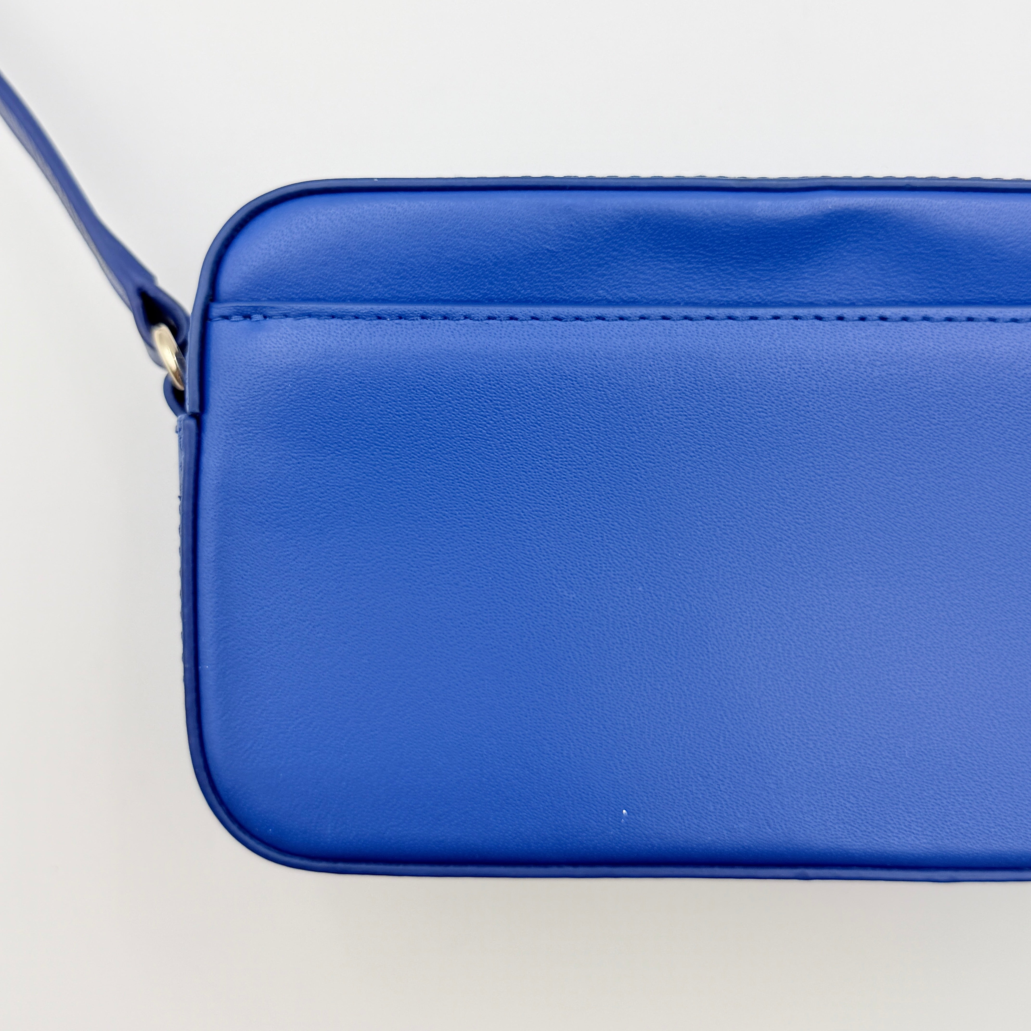 Furla Primula Mini Camera Crossbody Bag in vibrant blue leather with embossed logo, shown with adjustable strap.