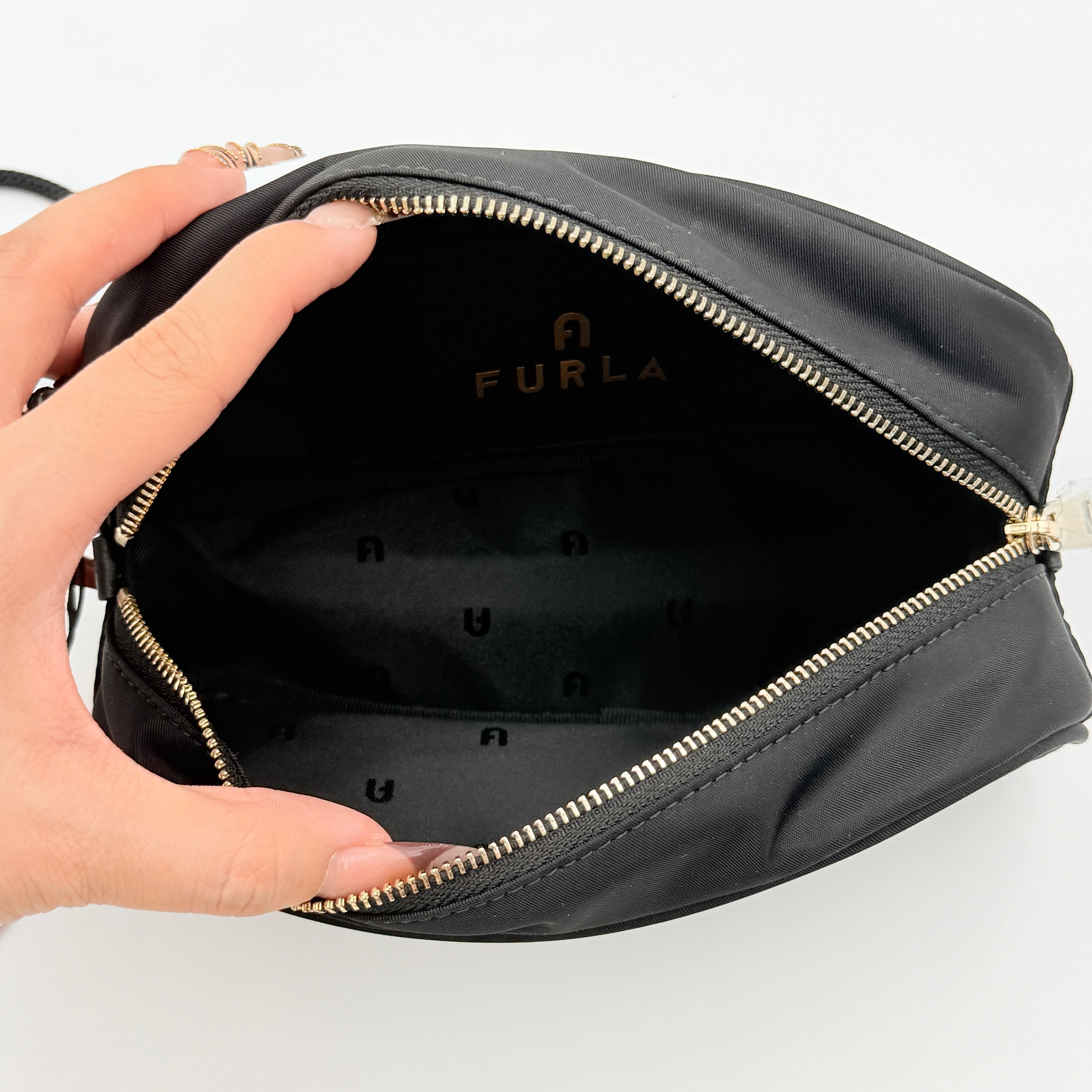 Furla Camelia Cosmetic Case in black nylon with gold logo and wristlet strap, shown with original tag.