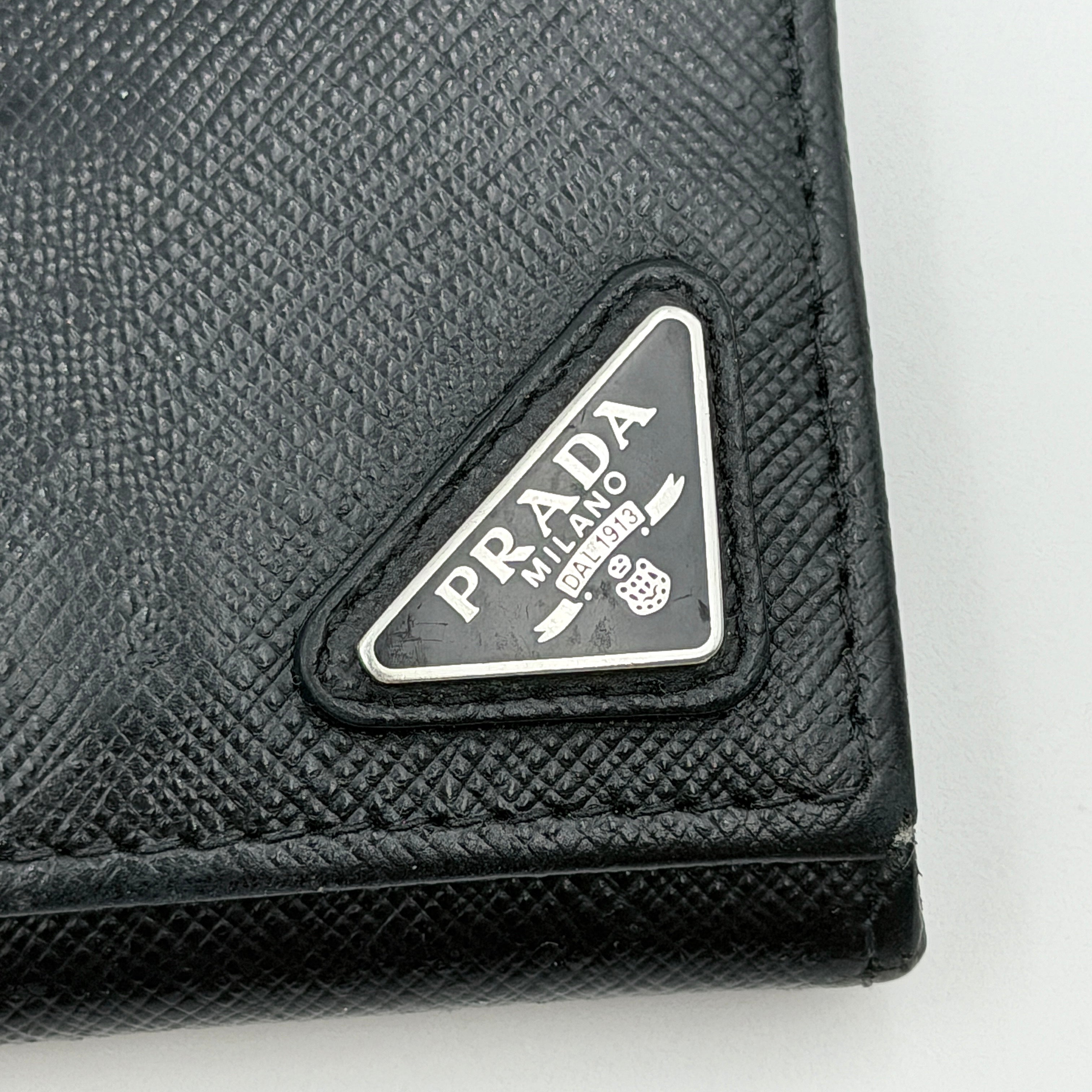 Prada Saffiano Triangle Logo Coin Case in black with silver enamel logo plaque at the corner.