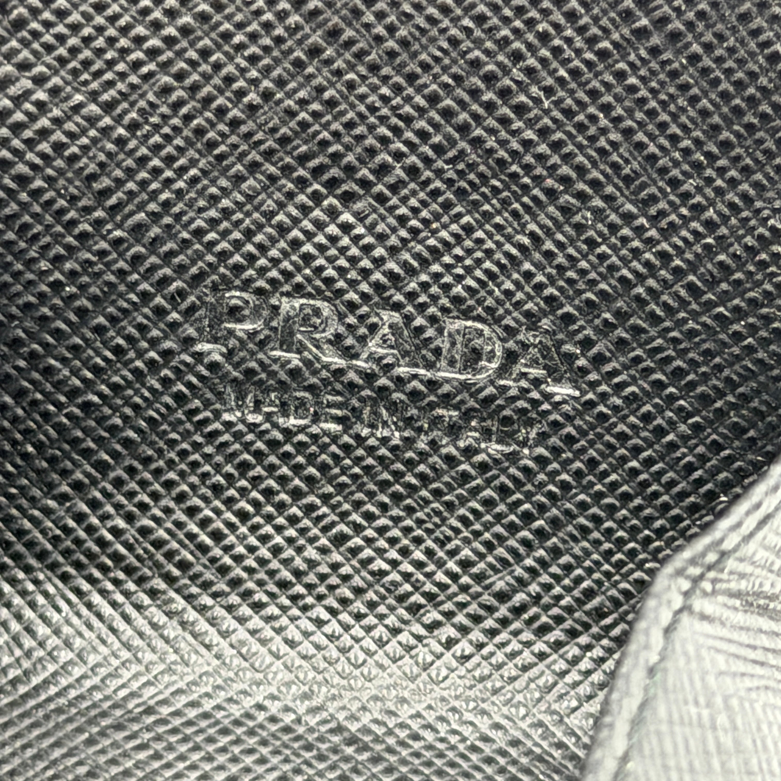 Prada Saffiano Triangle Logo Coin Case in black with silver enamel logo plaque at the corner.