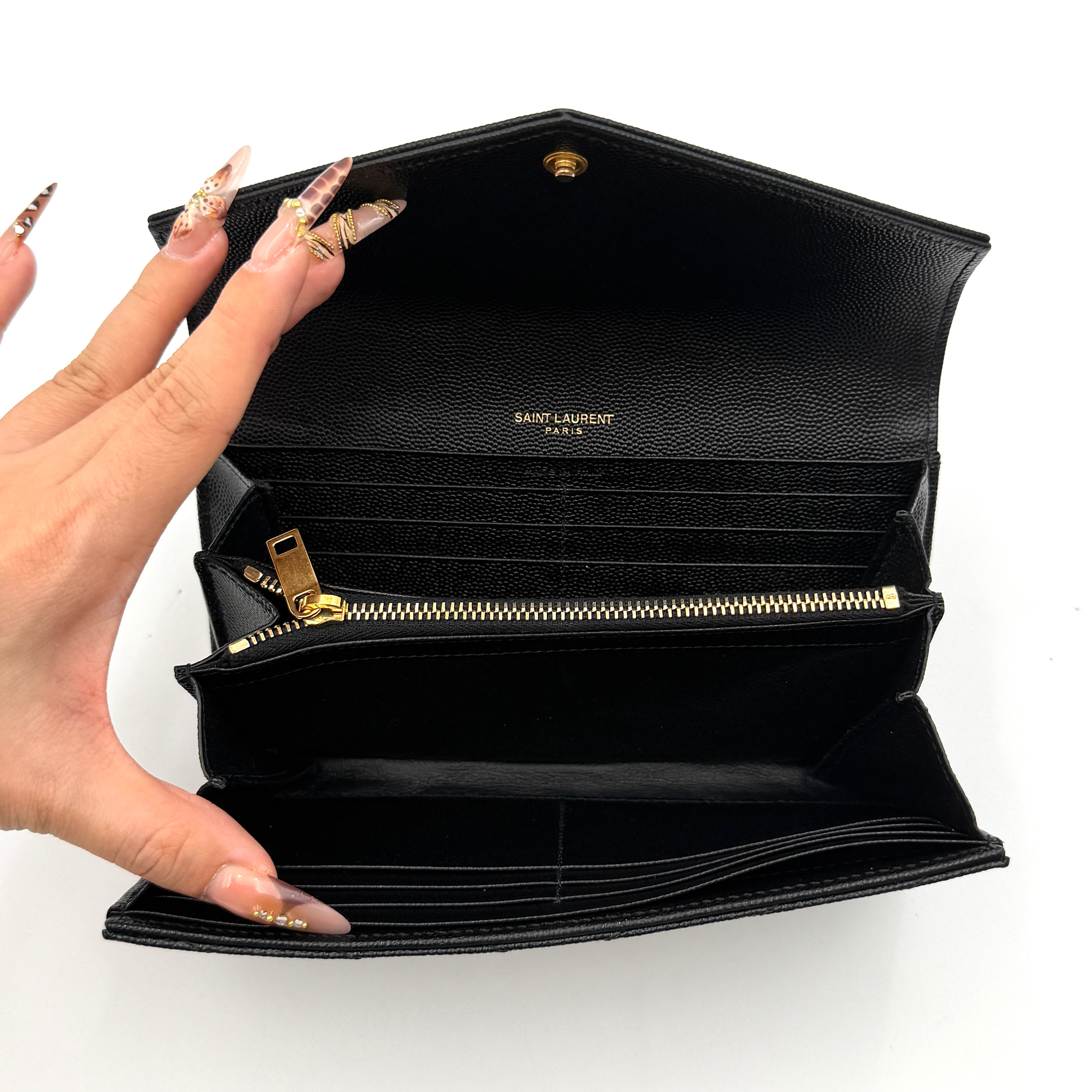Saint Laurent Cassandre Large Flap Wallet in black grained leather with gold YSL monogram and chevron quilting.