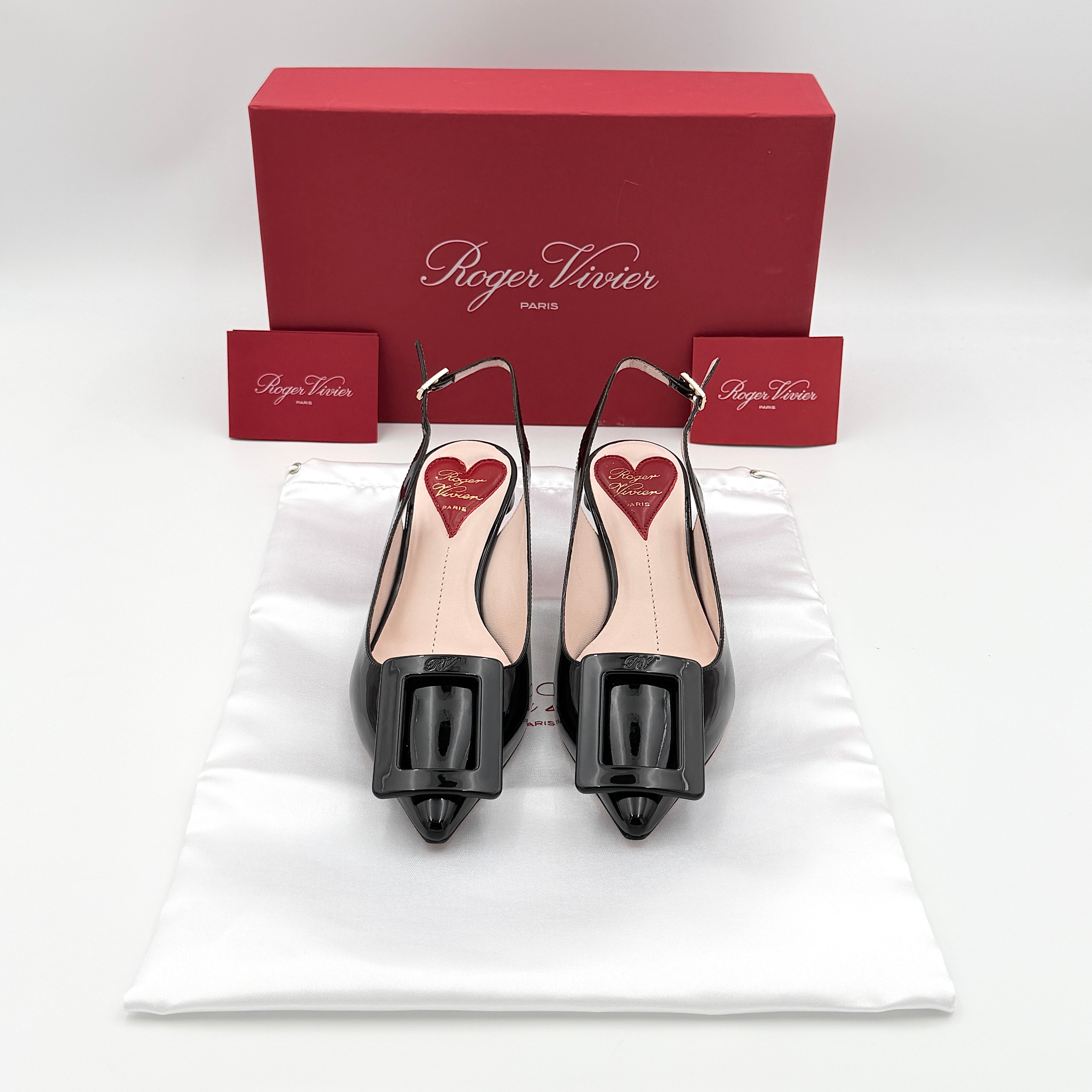 A pair of Roger Vivier Virgule black patent slingback pumps featuring a sculpted heel and oversized buckle at the toe.