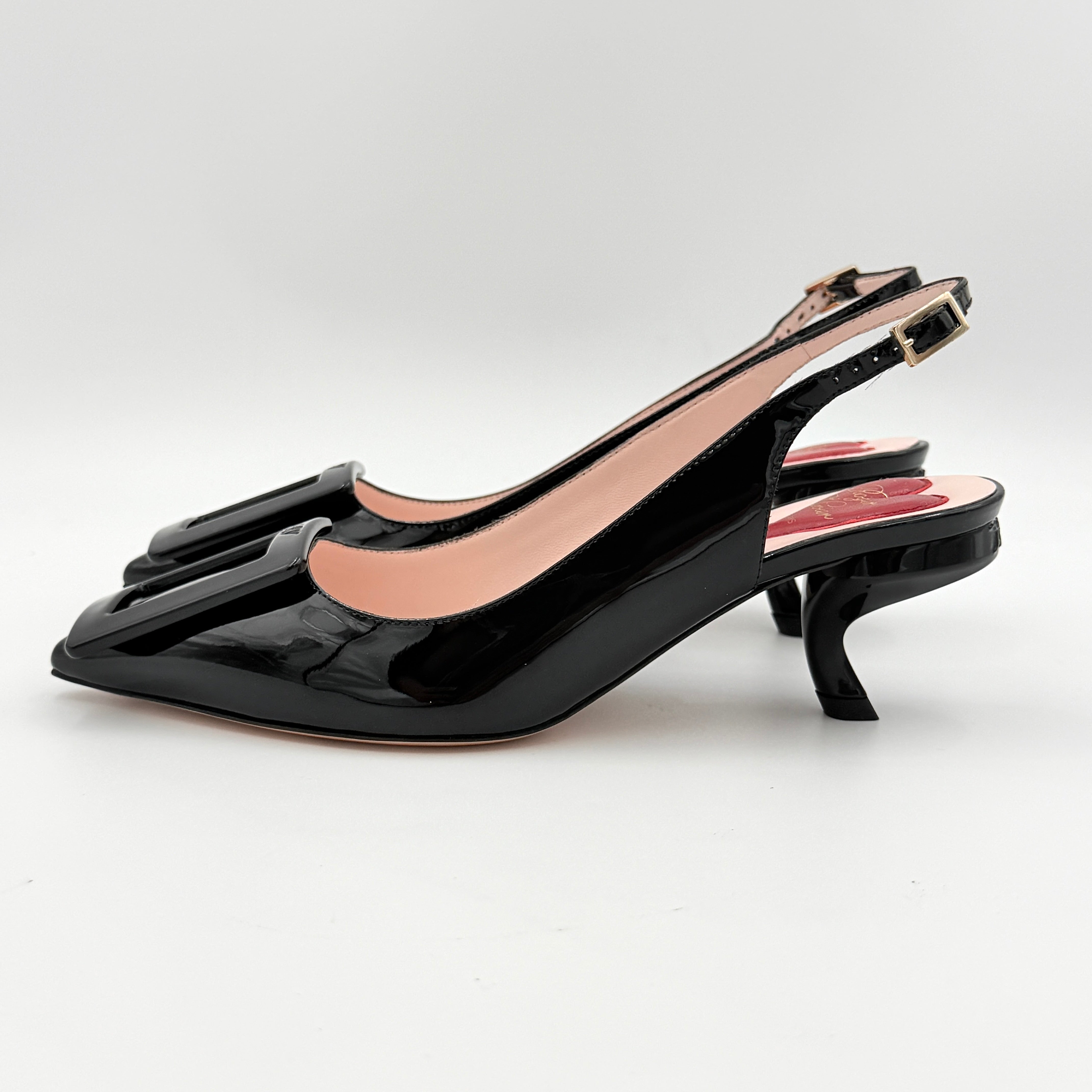 A pair of Roger Vivier Virgule black patent slingback pumps featuring a sculpted heel and oversized buckle at the toe.