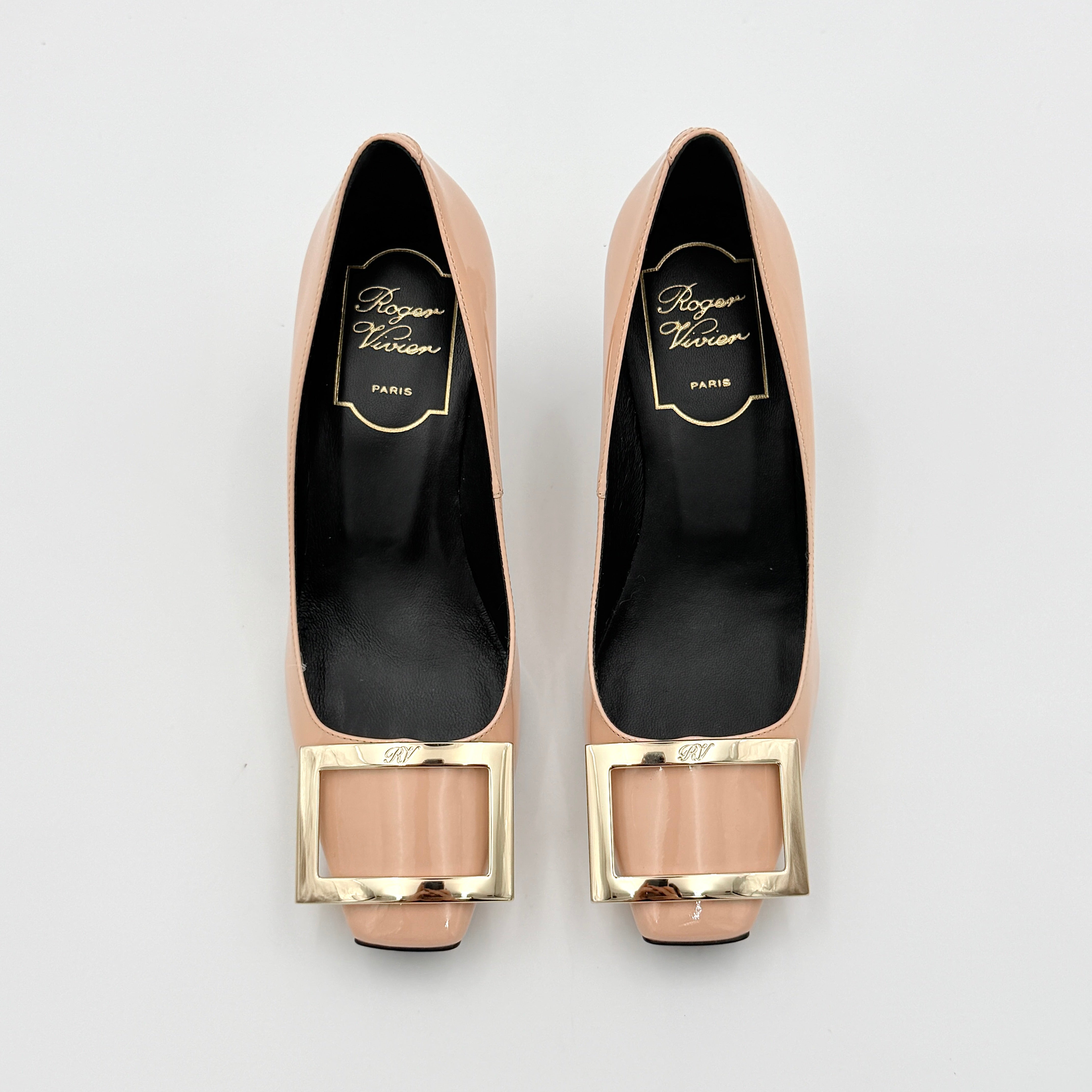 A pair of Roger Vivier Belle Vivier Trompette pumps in patent blush pink leather with signature gold buckles at the toe.