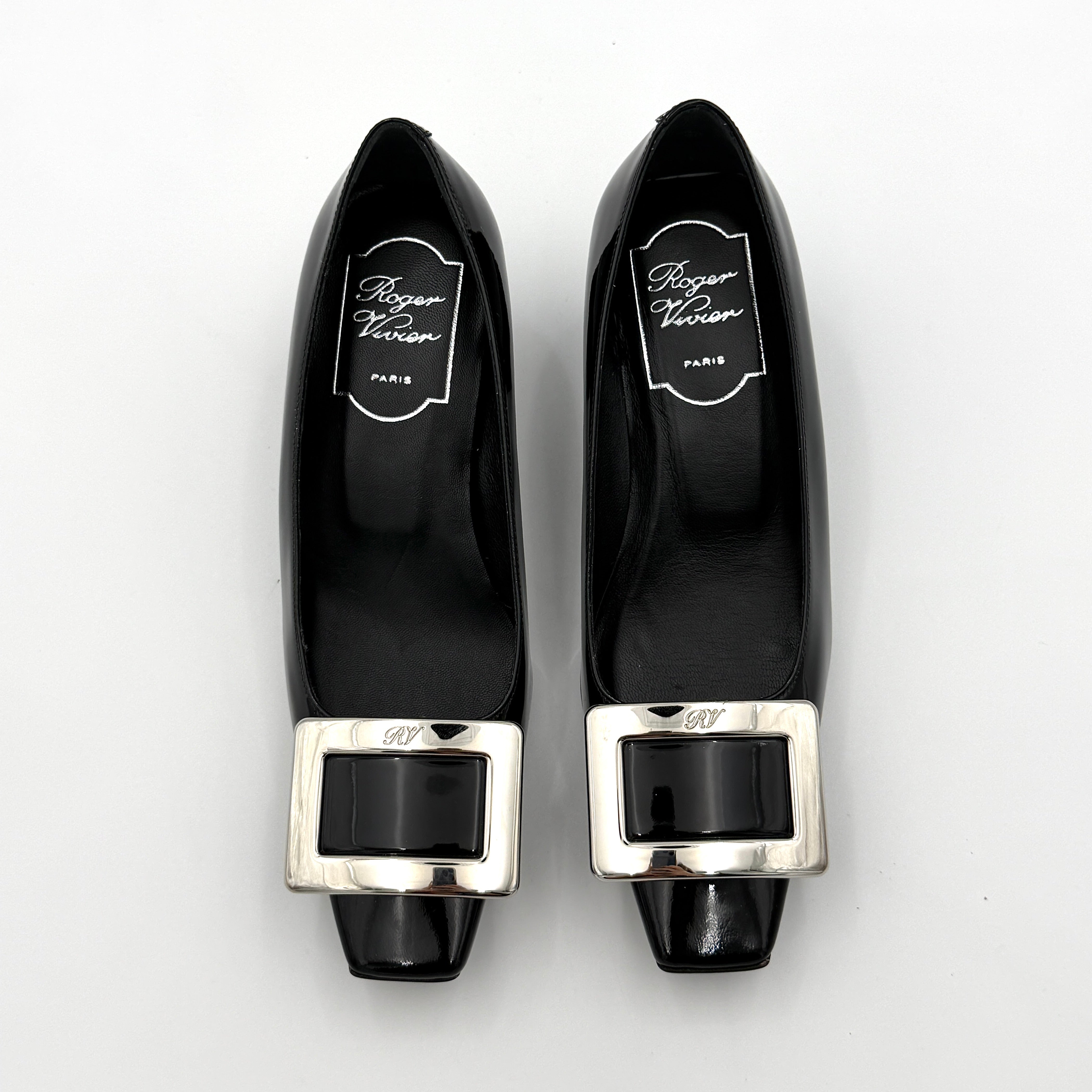 A pair of Roger Vivier Belle Vivier black patent pumps with signature silver-tone buckles, displayed at an angle.