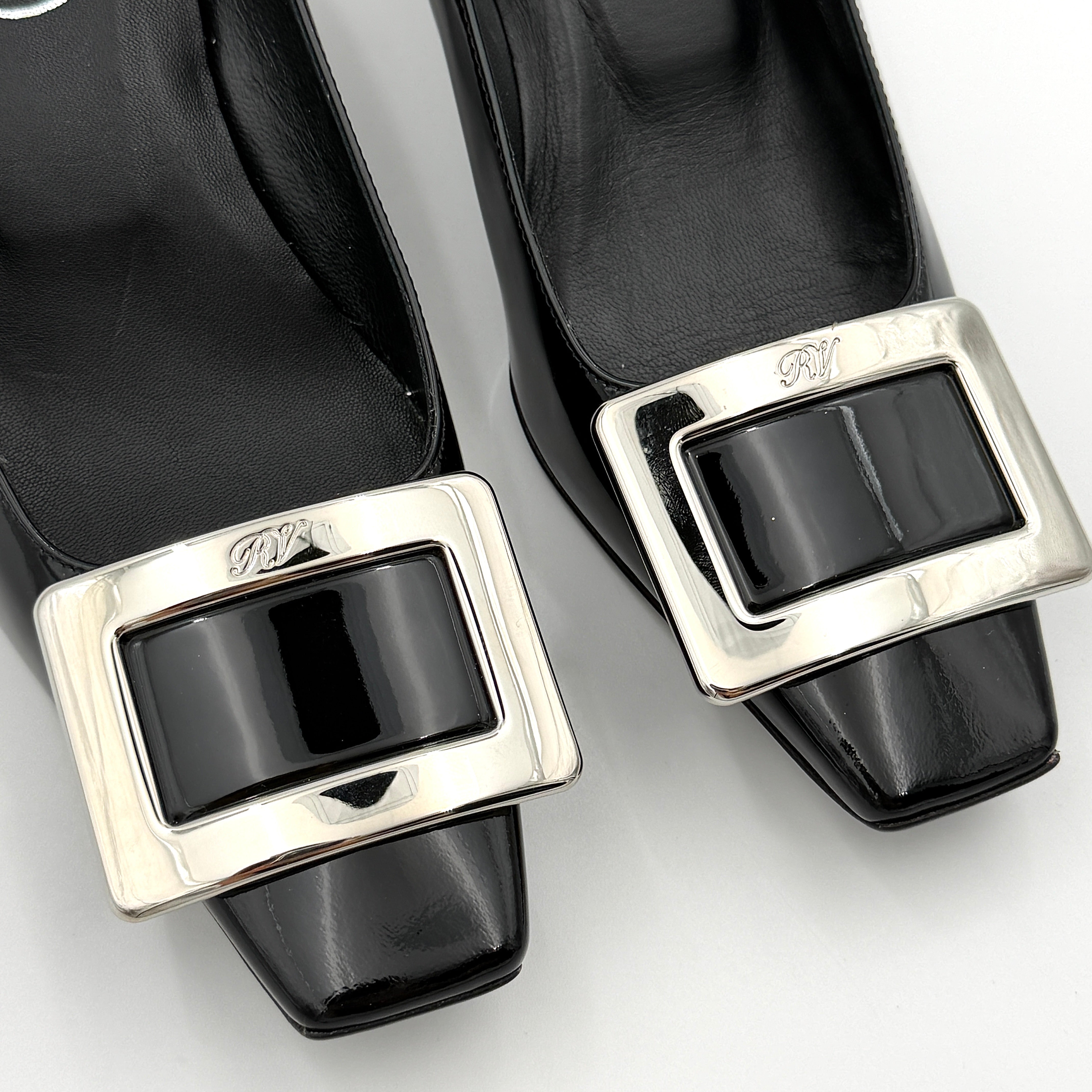 A pair of Roger Vivier Belle Vivier black patent pumps with signature silver-tone buckles, displayed at an angle.