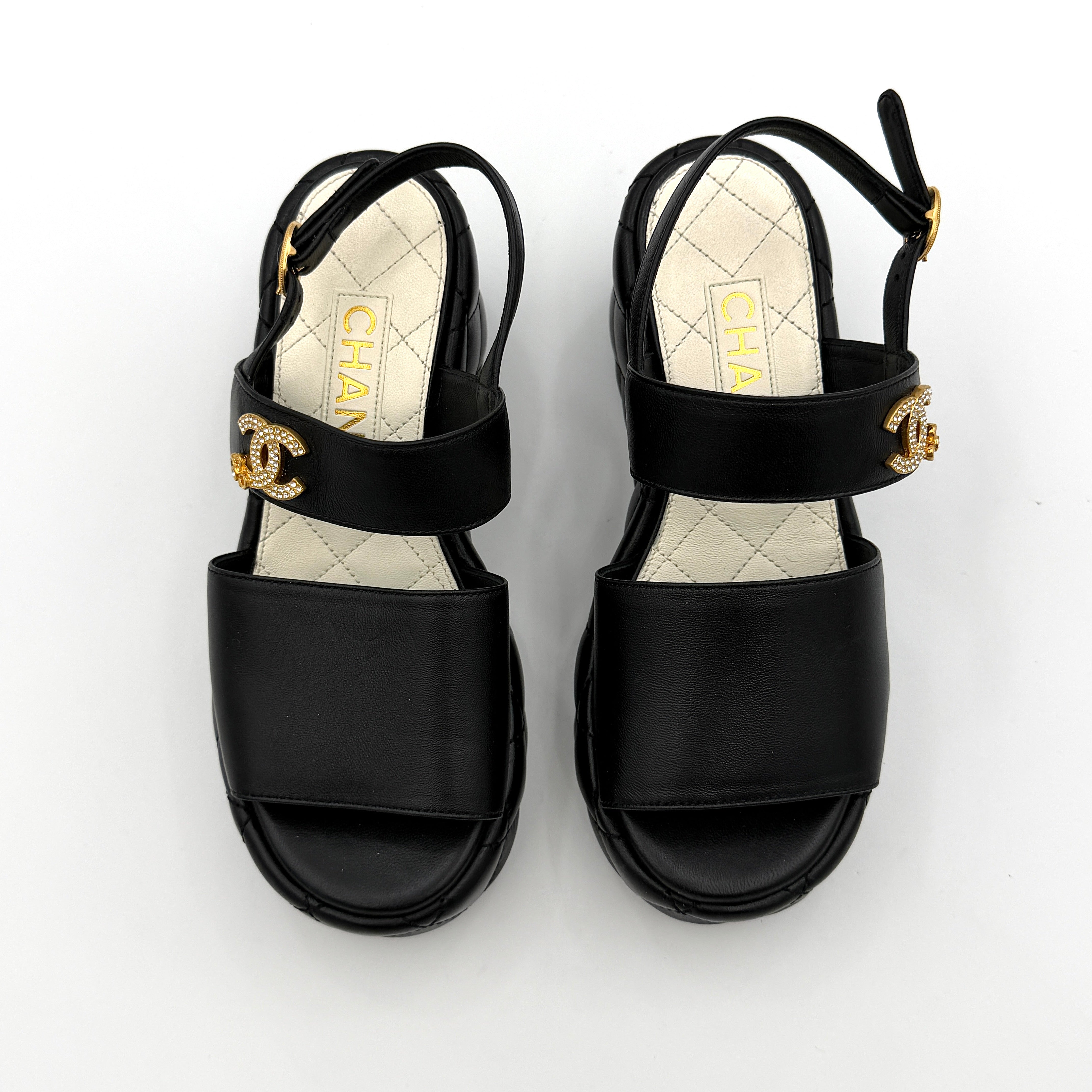 Chanel black quilted leather wedge platform sandals with gold crystal CC hardware and ankle strap detailing.