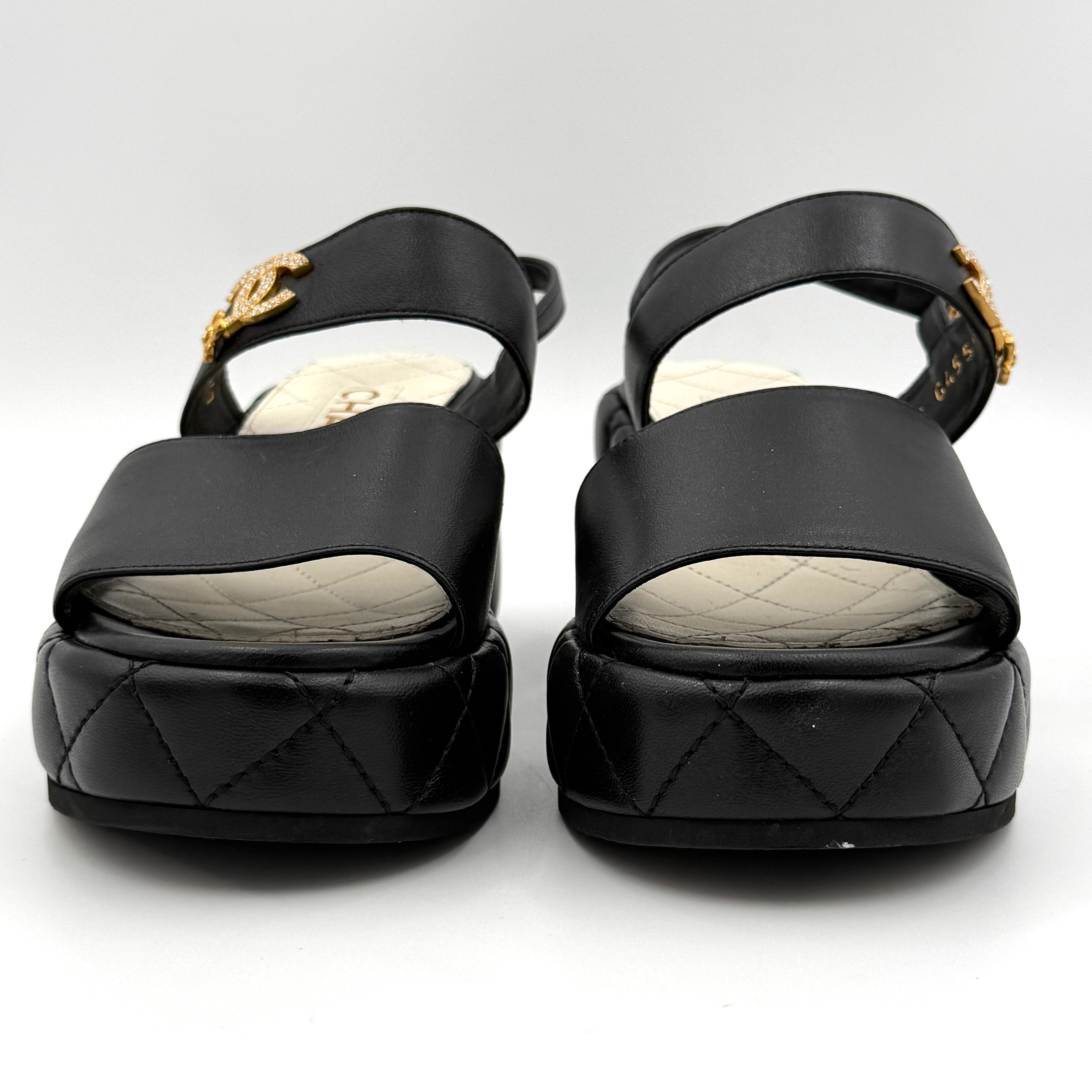 Chanel black quilted leather wedge platform sandals with gold crystal CC hardware and ankle strap detailing.