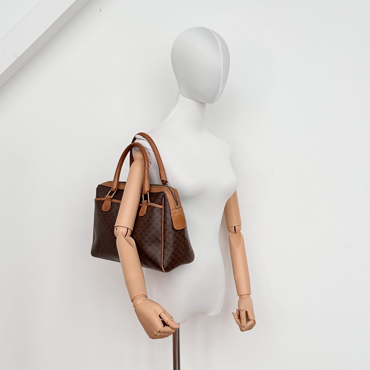 Celine Triomphe Macadam Boston Bag in brown coated canvas with tan leather trim and top handles, photographed against a white background.