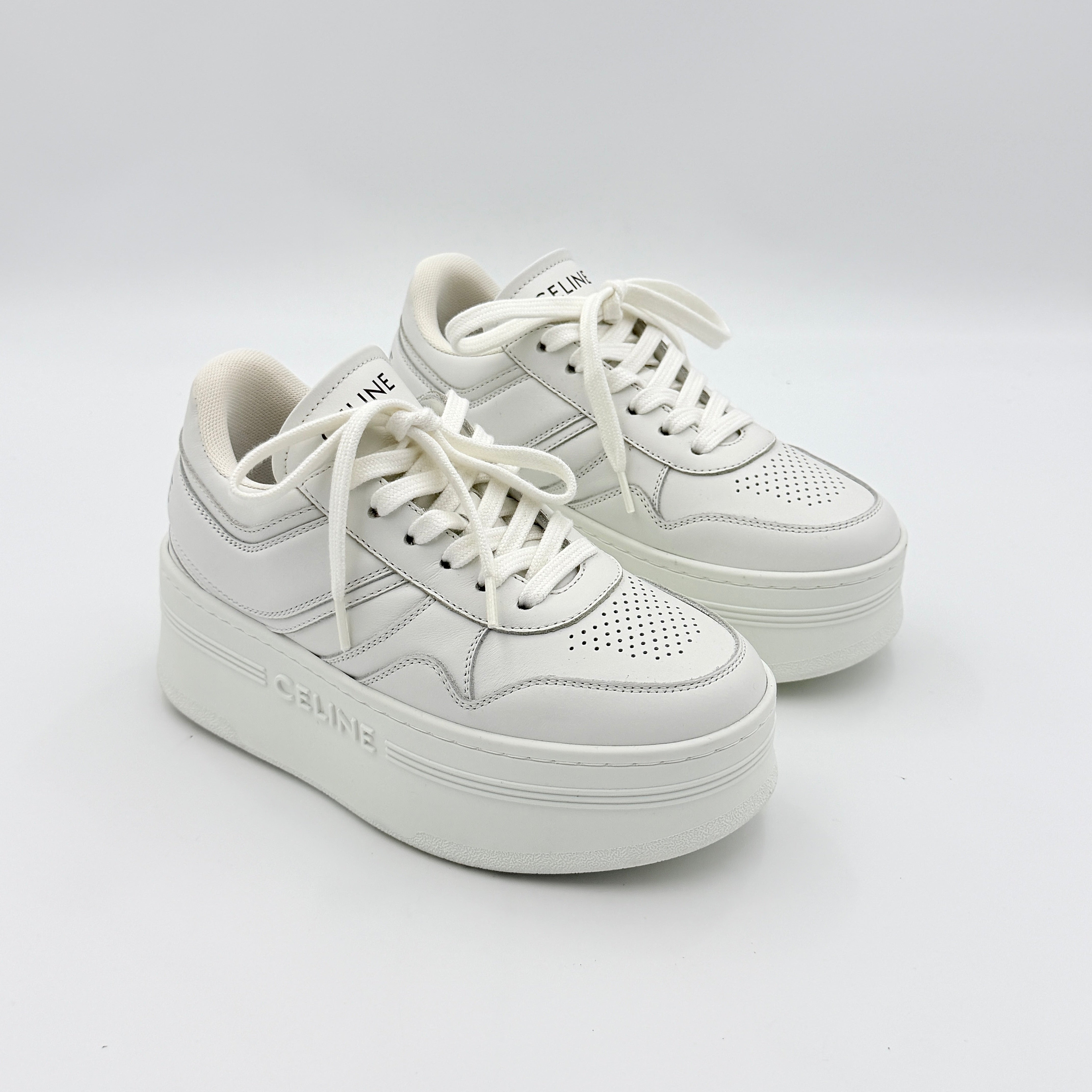 Celine white leather block platform sneakers with bold embossed sole and lace-up front, displayed at a slight angle.