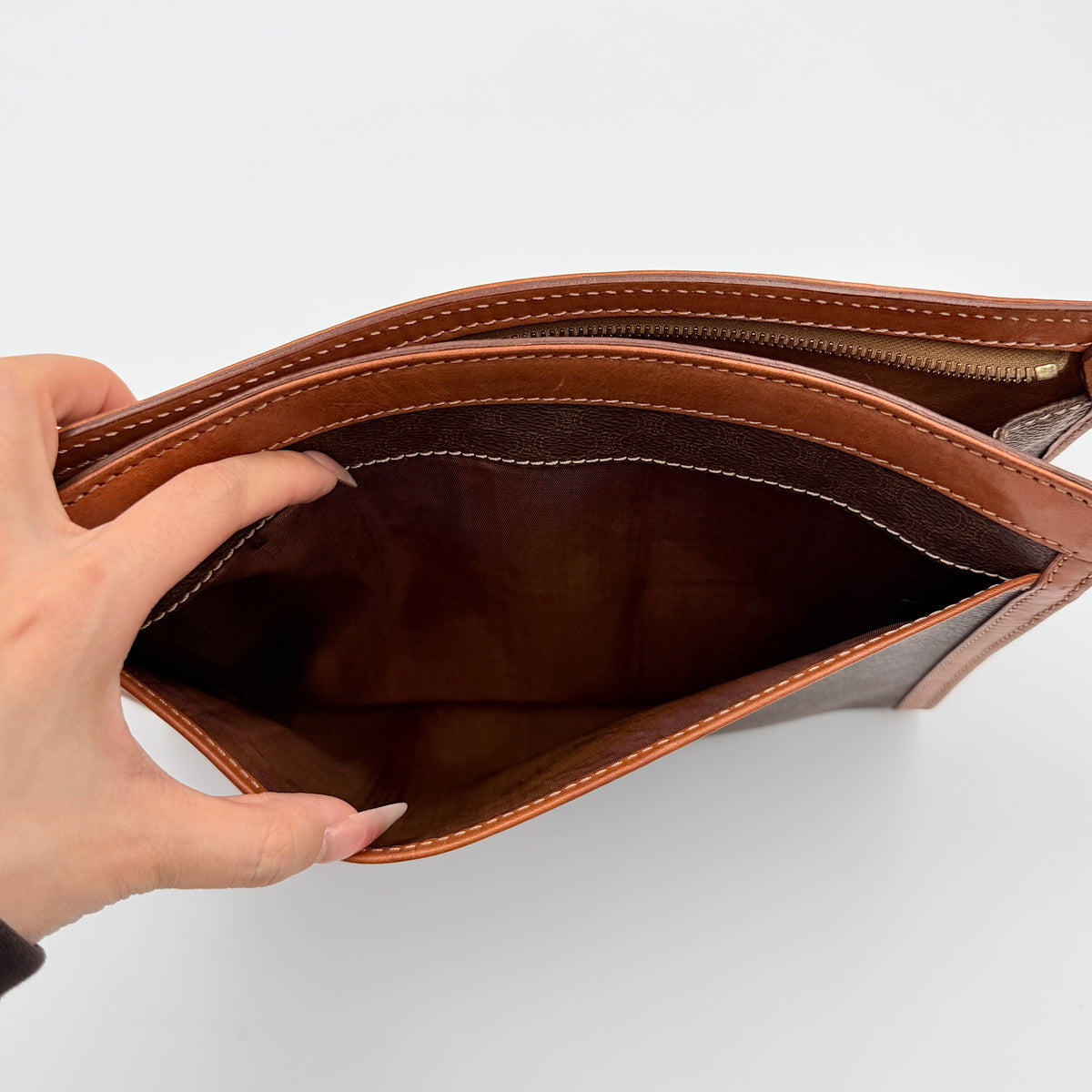 Celine Triomphe Macadam Clutch Bag in brown coated canvas with tan leather trim and gold zip, displayed against a white background.