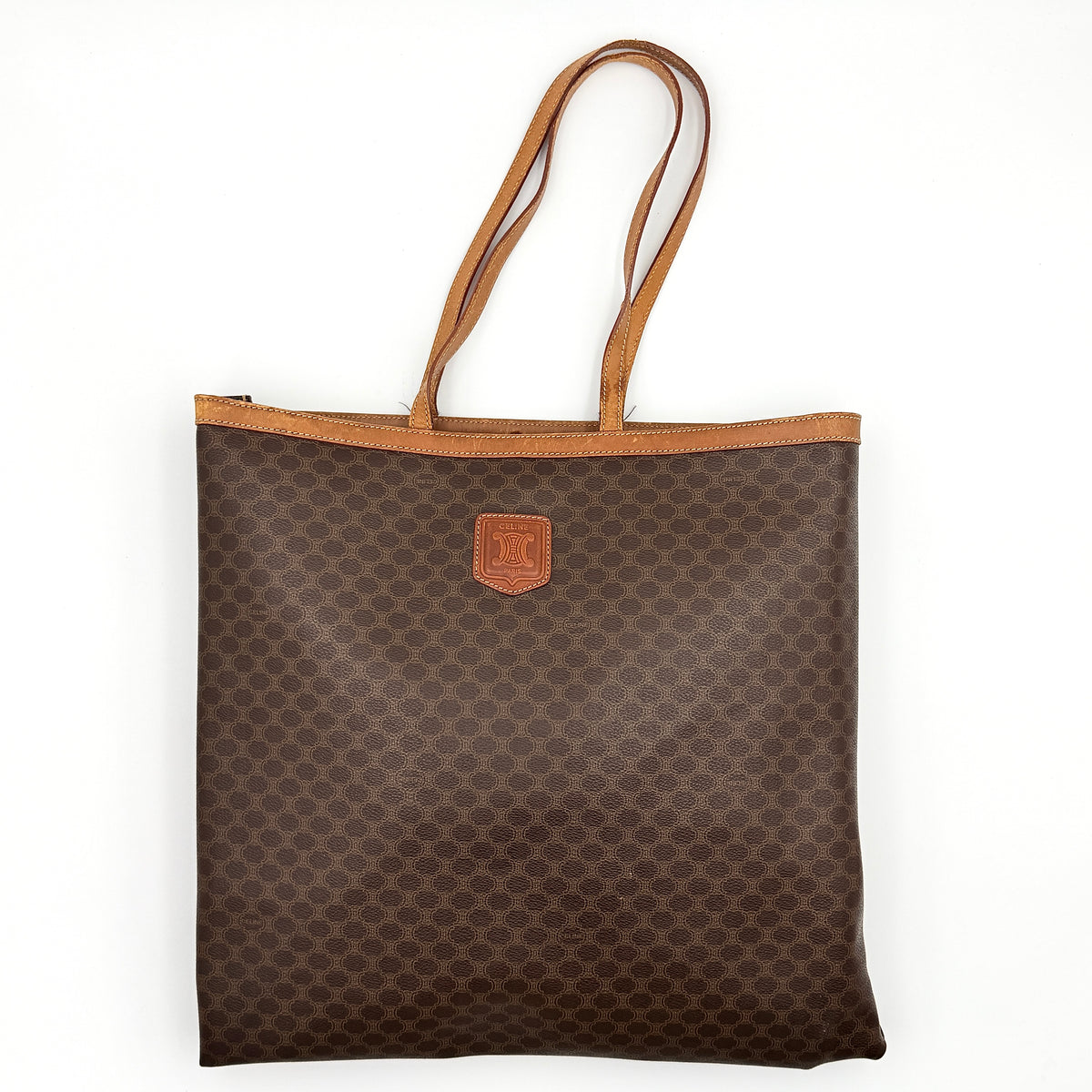 Front view of the Celine Triomphe Macadam Tote Bag in brown coated canvas with tan leather detailing and double handles.