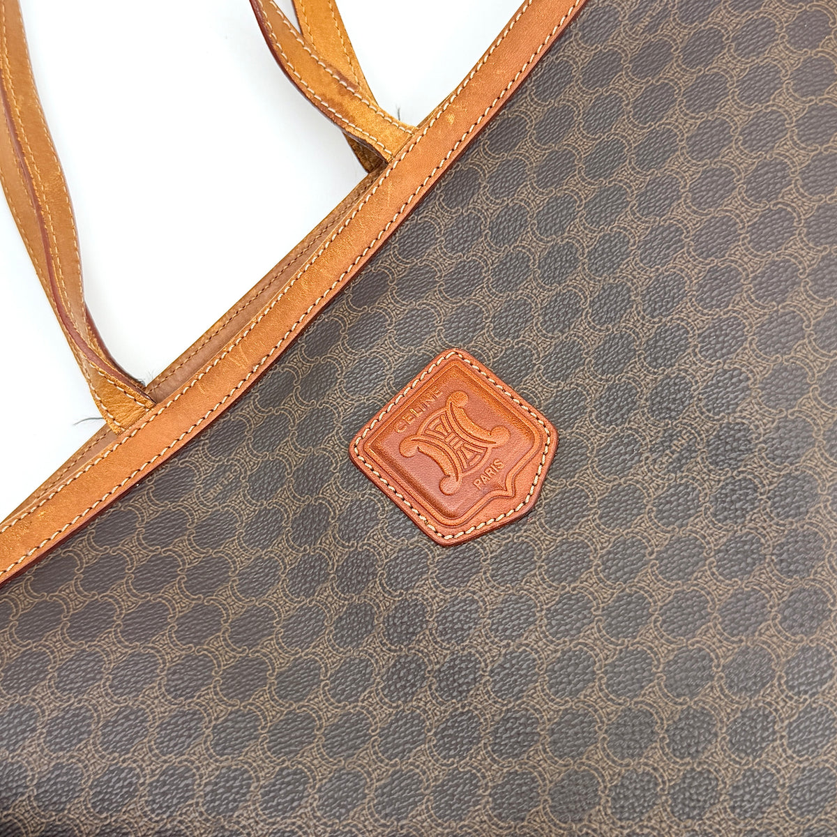 Front view of the Celine Triomphe Macadam Tote Bag in brown coated canvas with tan leather detailing and double handles.