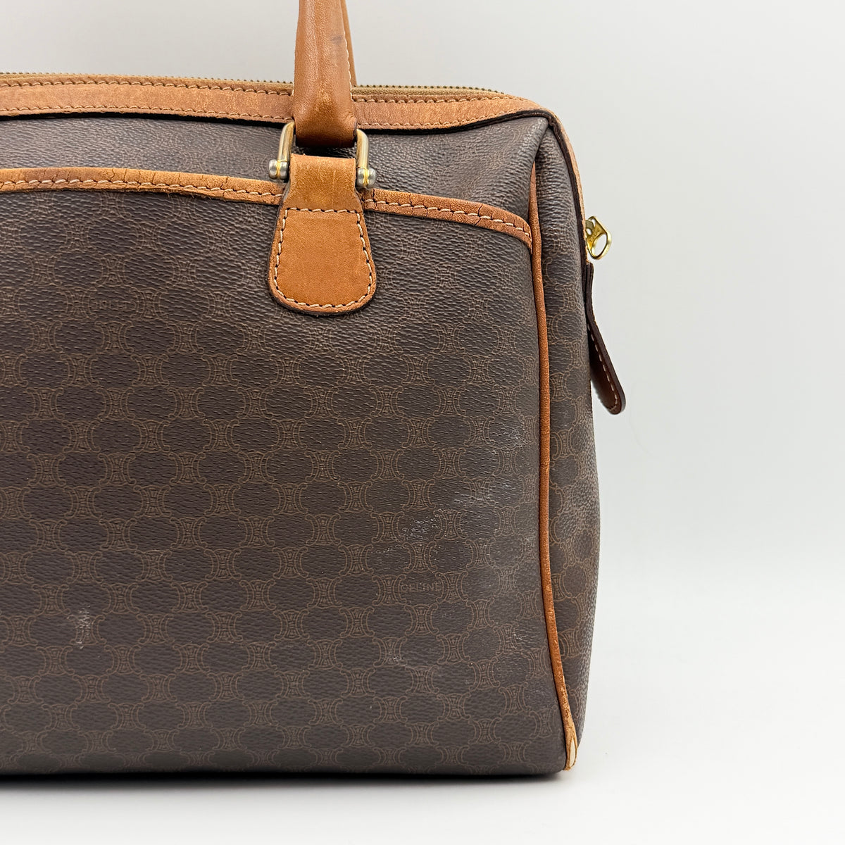 Celine Triomphe Macadam Boston Bag in brown coated canvas with tan leather trim and top handles, photographed against a white background.