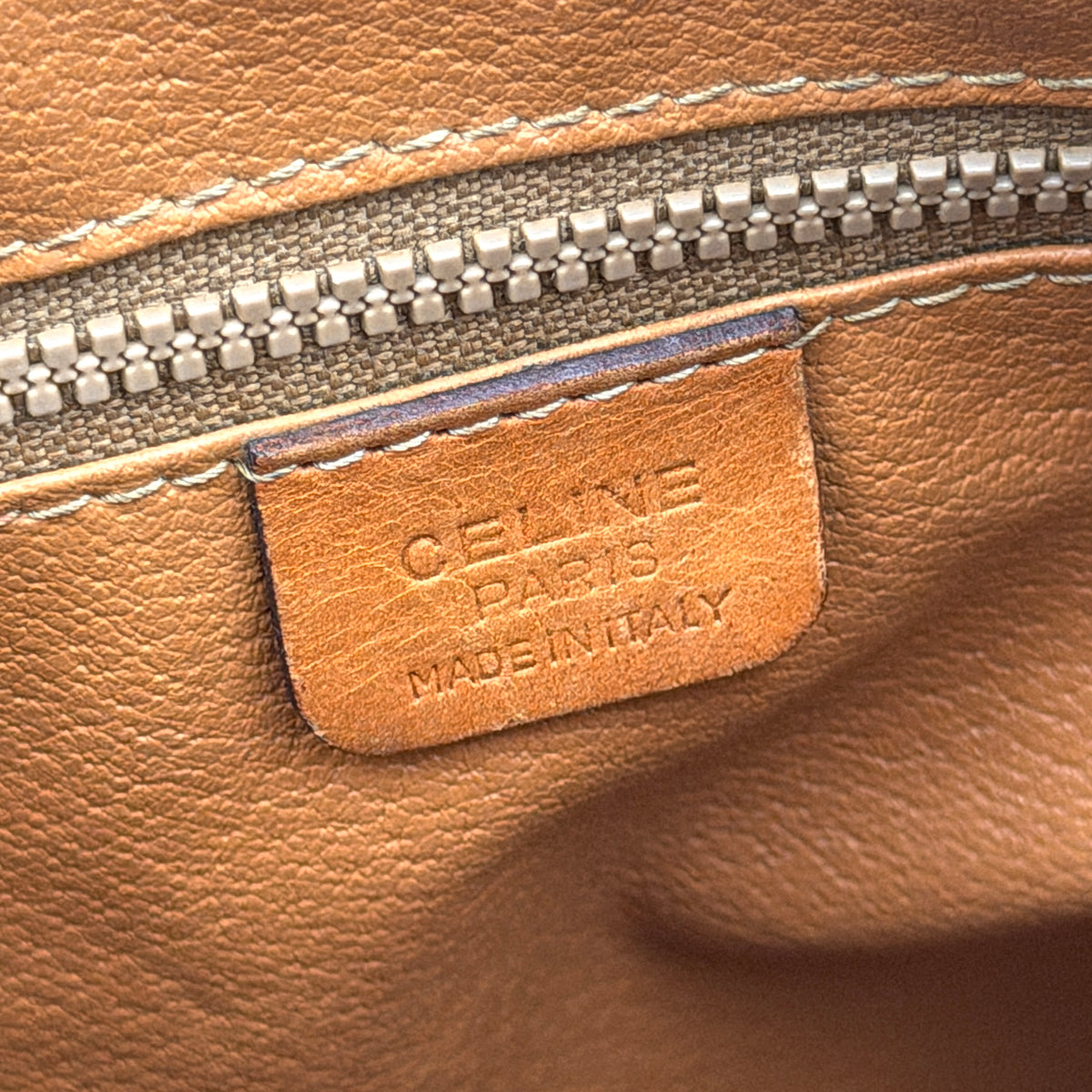 Celine Triomphe Macadam Boston Bag in brown coated canvas with tan leather trim and top handles, photographed against a white background.