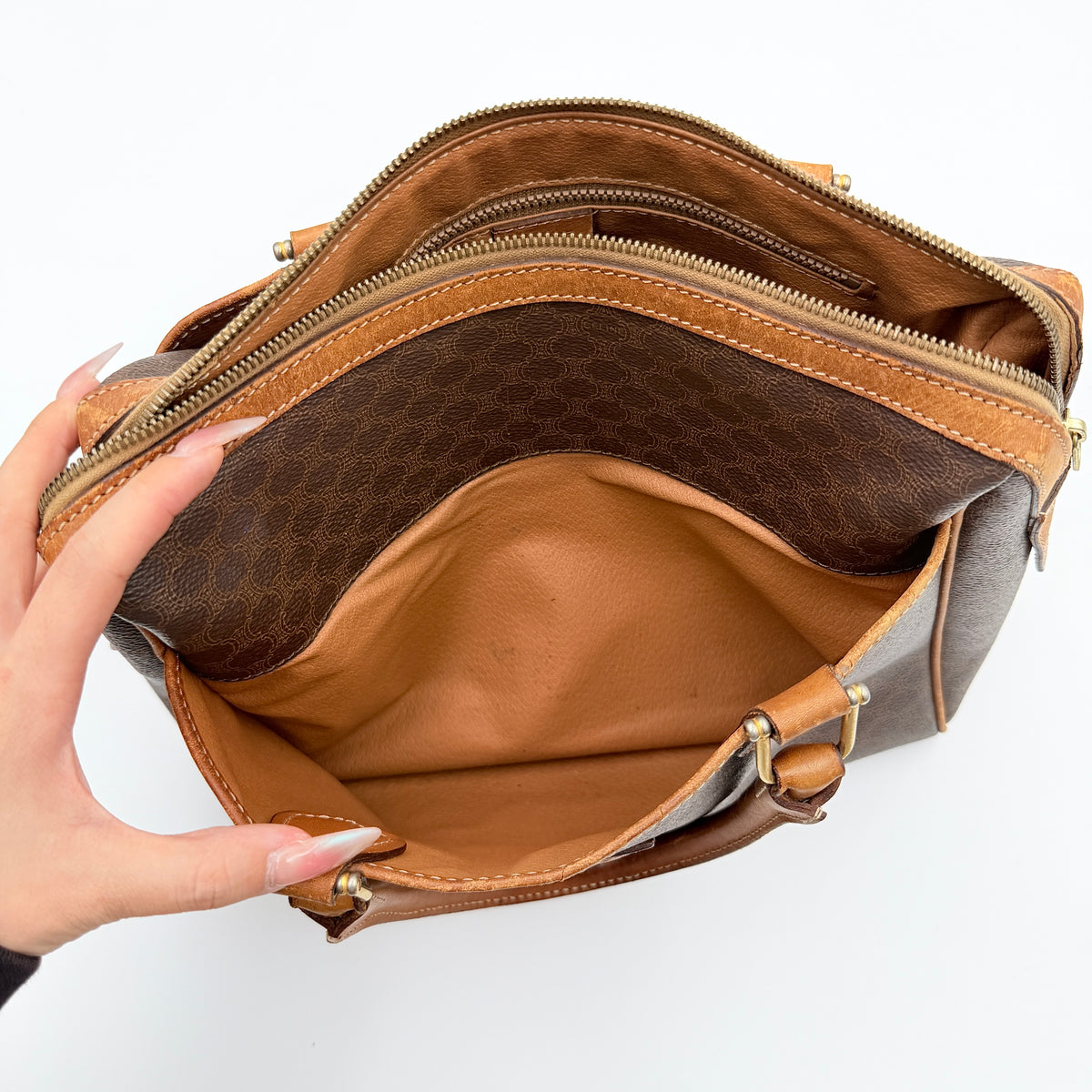 Celine Triomphe Macadam Boston Bag in brown coated canvas with tan leather trim and top handles, photographed against a white background.