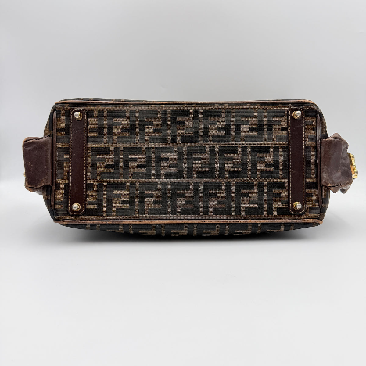 Fendi FF Zucca Double Zip Tote Bag in brown monogram canvas with leather straps and side pocket detail, shown on a yellow dust bag.