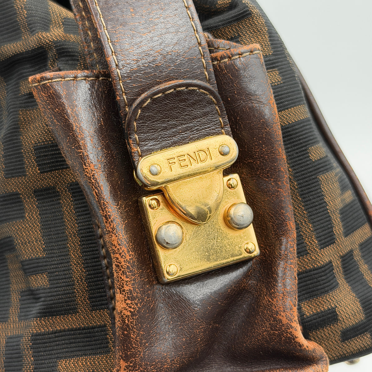 Fendi FF Zucca Double Zip Tote Bag in brown monogram canvas with leather straps and side pocket detail, shown on a yellow dust bag.