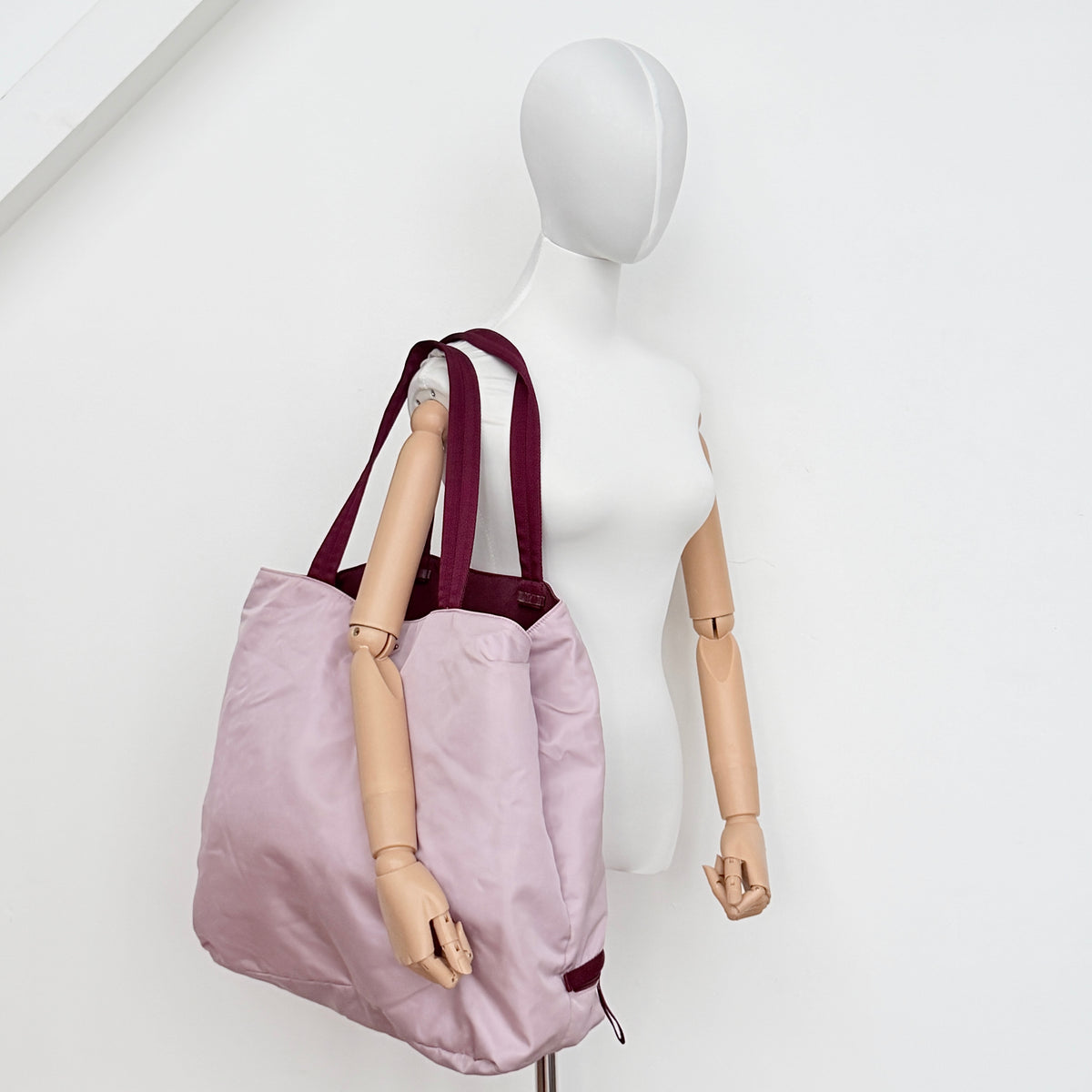 Prada pink nylon tote bag with berry handles photographed against a white background.