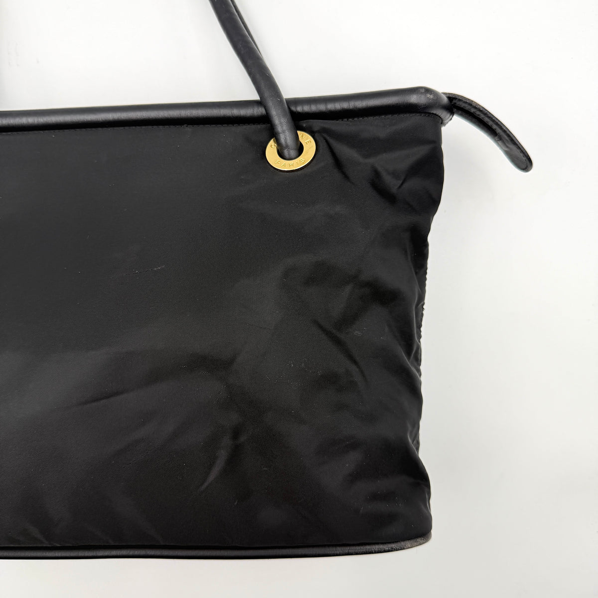Black Celine nylon tote bag with gold circle logo hardware and leather handles, photographed flat on a white background.
