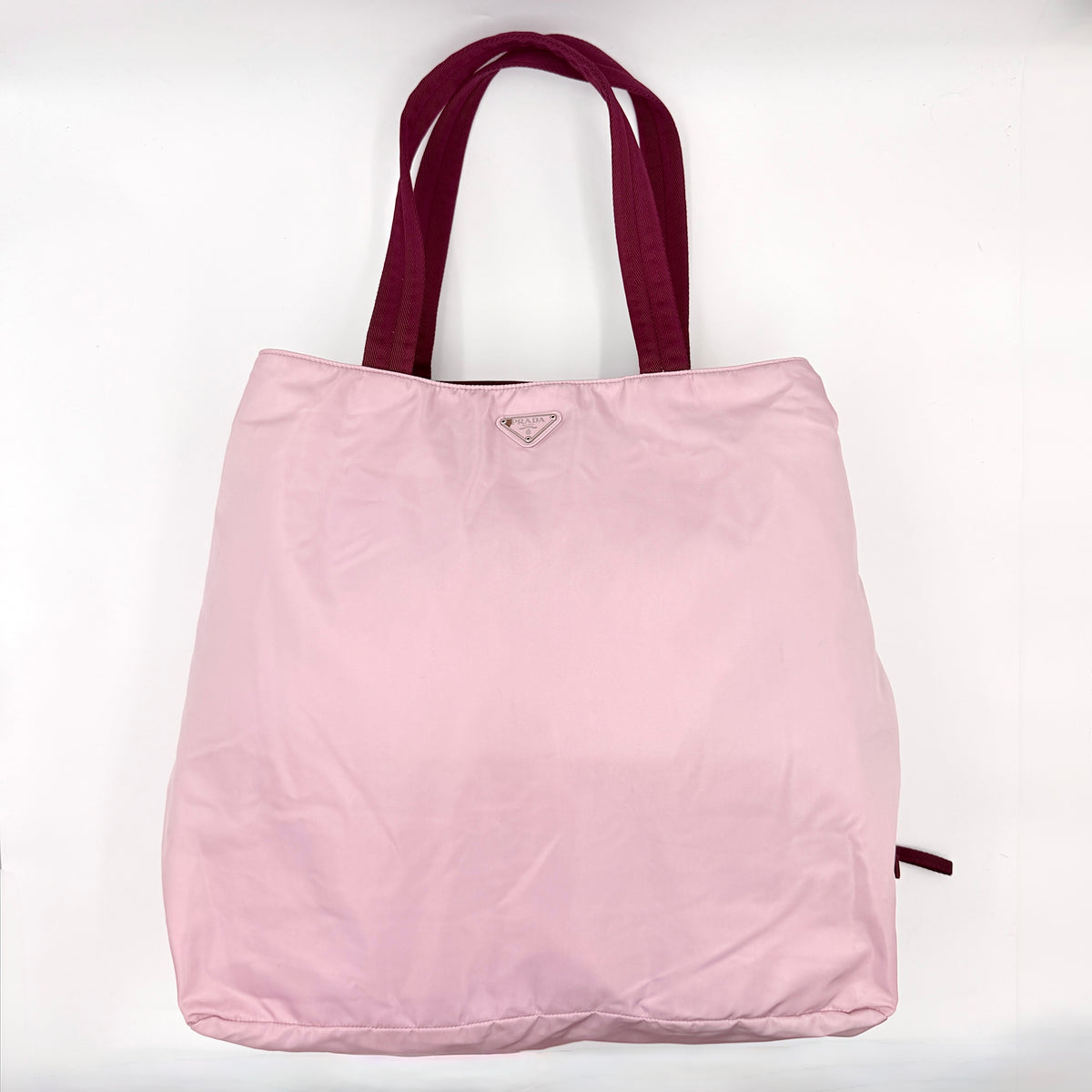Prada pink nylon tote bag with berry handles photographed against a white background.