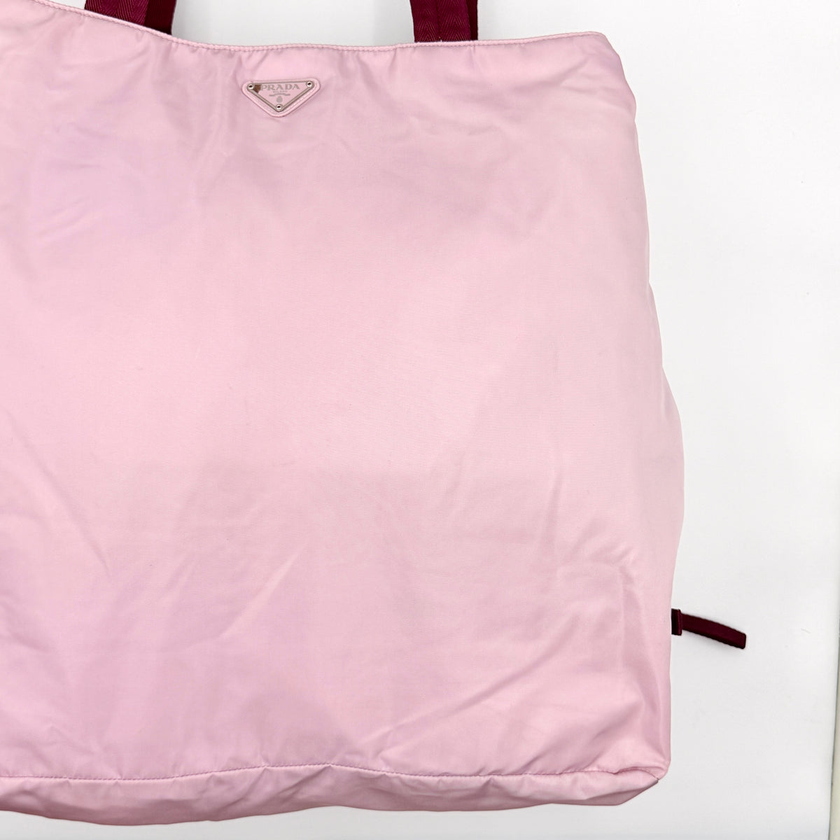 Prada pink nylon tote bag with berry handles photographed against a white background.