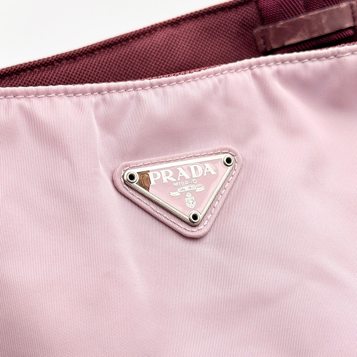 Prada pink nylon tote bag with berry handles photographed against a white background.
