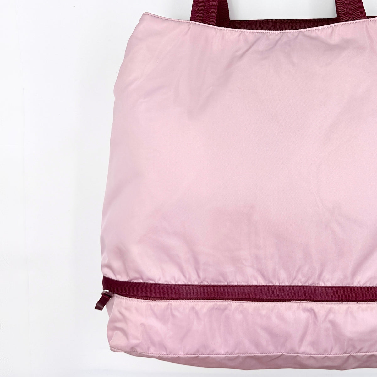 Prada pink nylon tote bag with berry handles photographed against a white background.