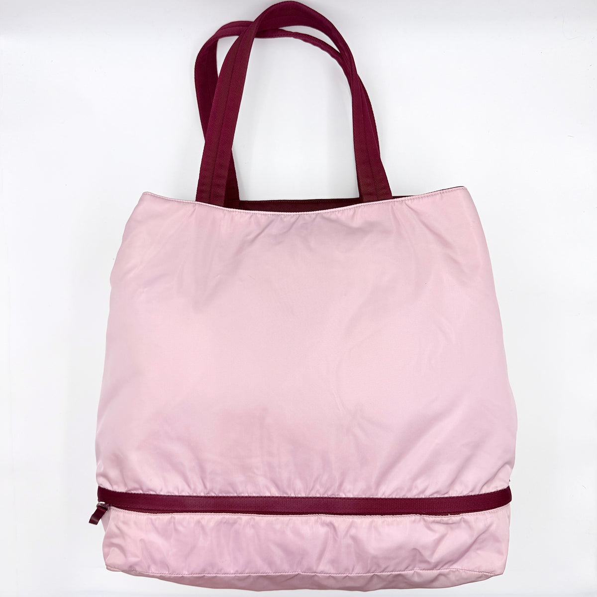 Prada pink nylon tote bag with berry handles photographed against a white background.