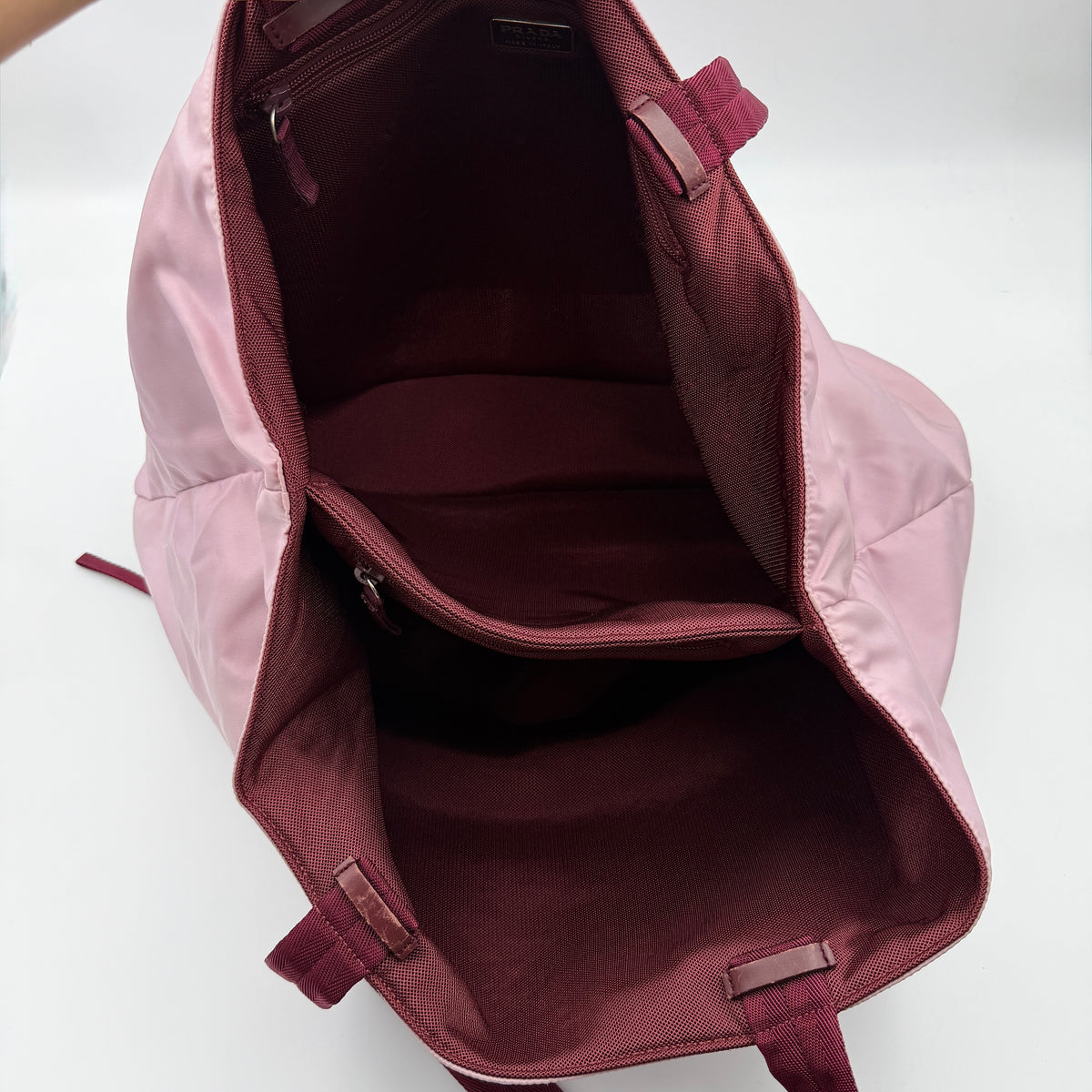 Prada pink nylon tote bag with berry handles photographed against a white background.