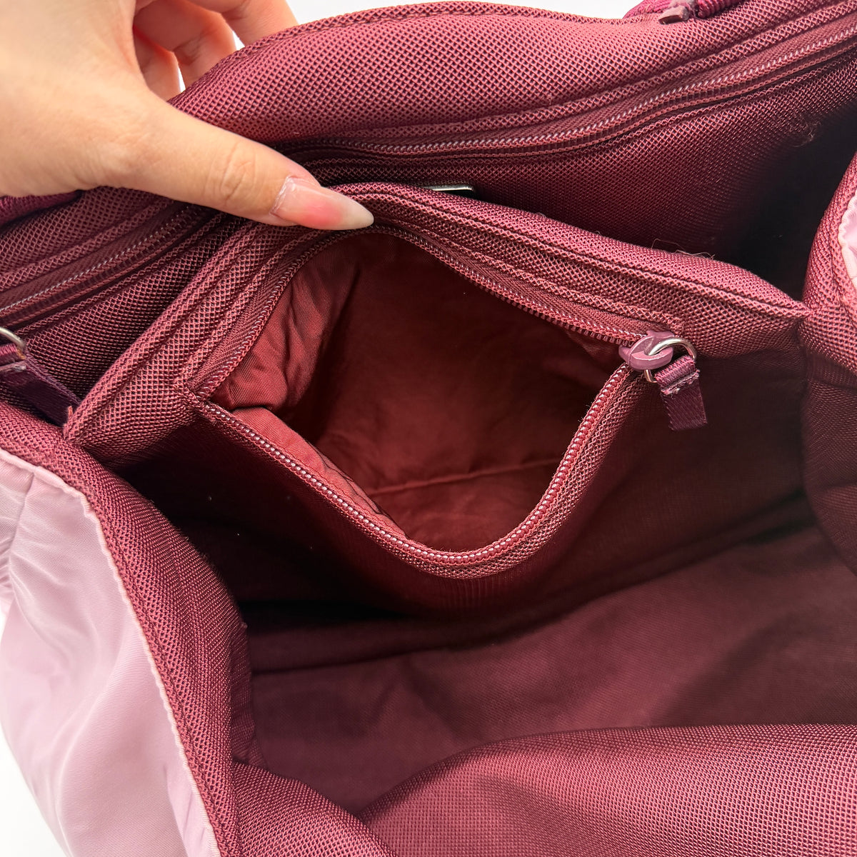 Prada pink nylon tote bag with berry handles photographed against a white background.