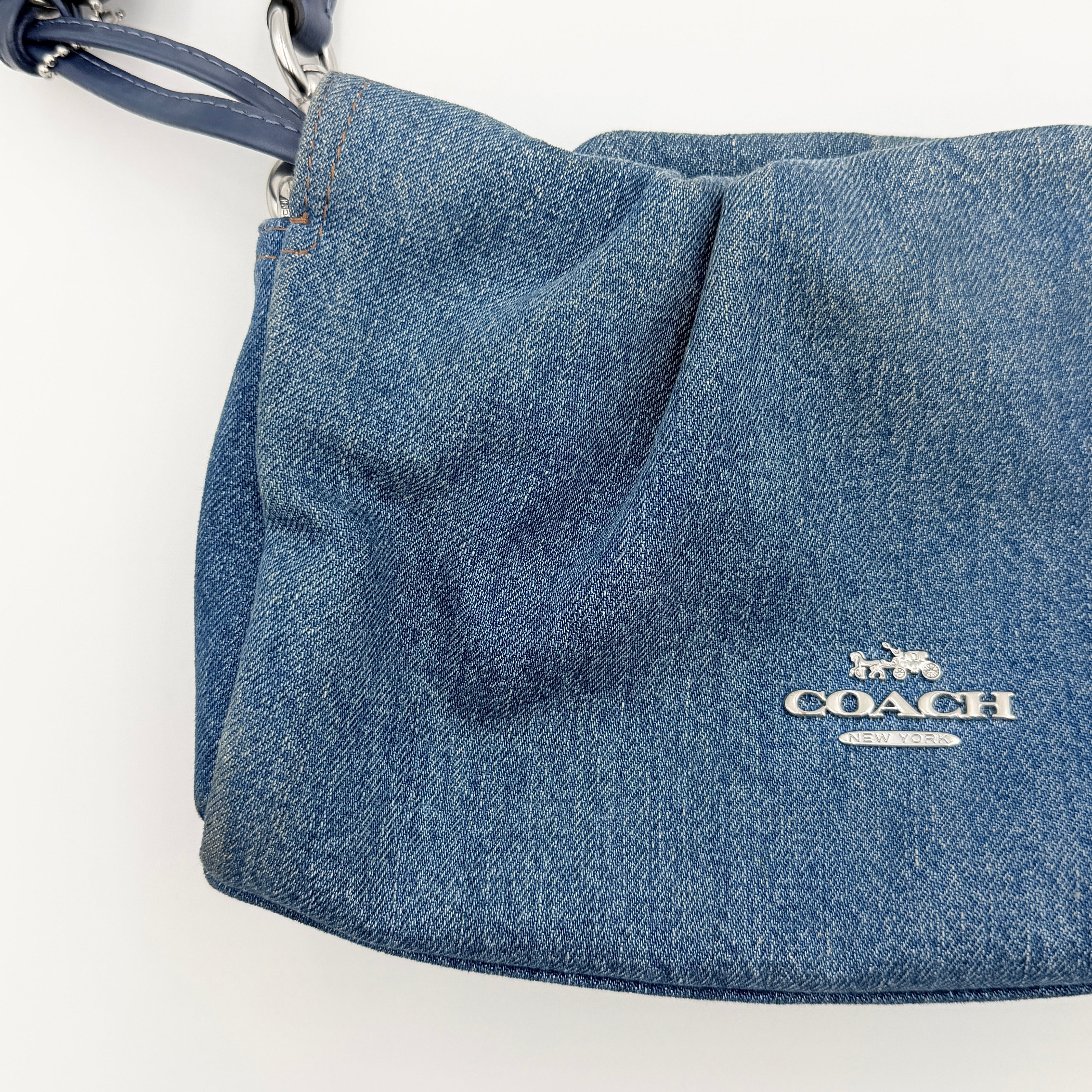 Coach Faye Shoulder Bag in blue denim with navy leather strap and detachable crossbody, styled simply against a white background.