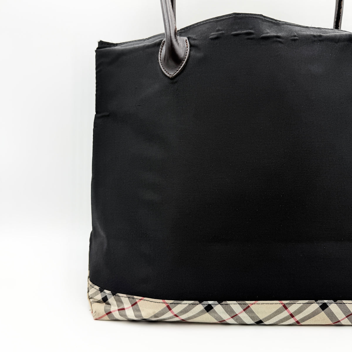 Burberry Blue Label black nylon tote bag with leather handles and nova check trim at the base.