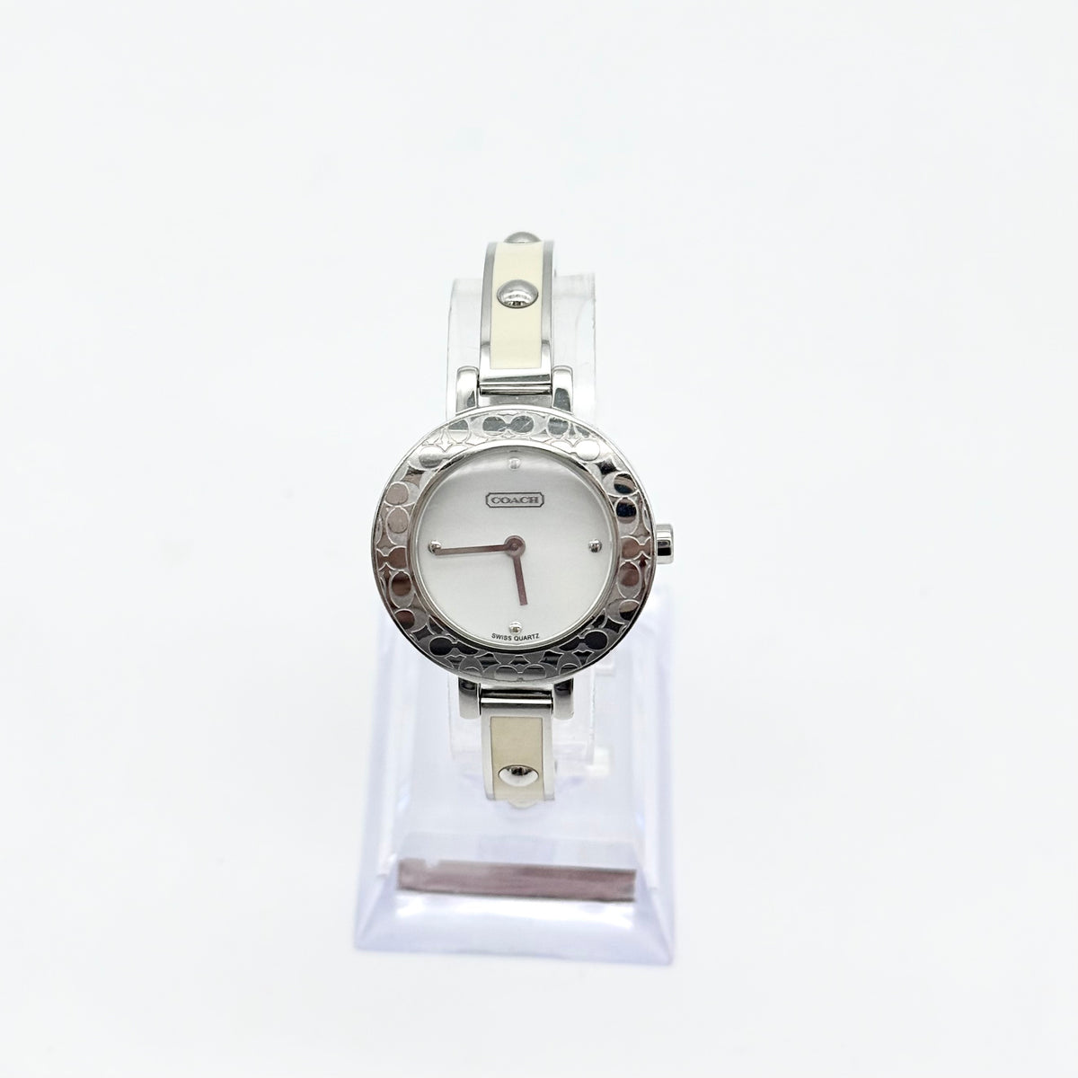 Coach Signature C Bangle Watch in cream and silver featuring a round face and polished bangle bracelet.