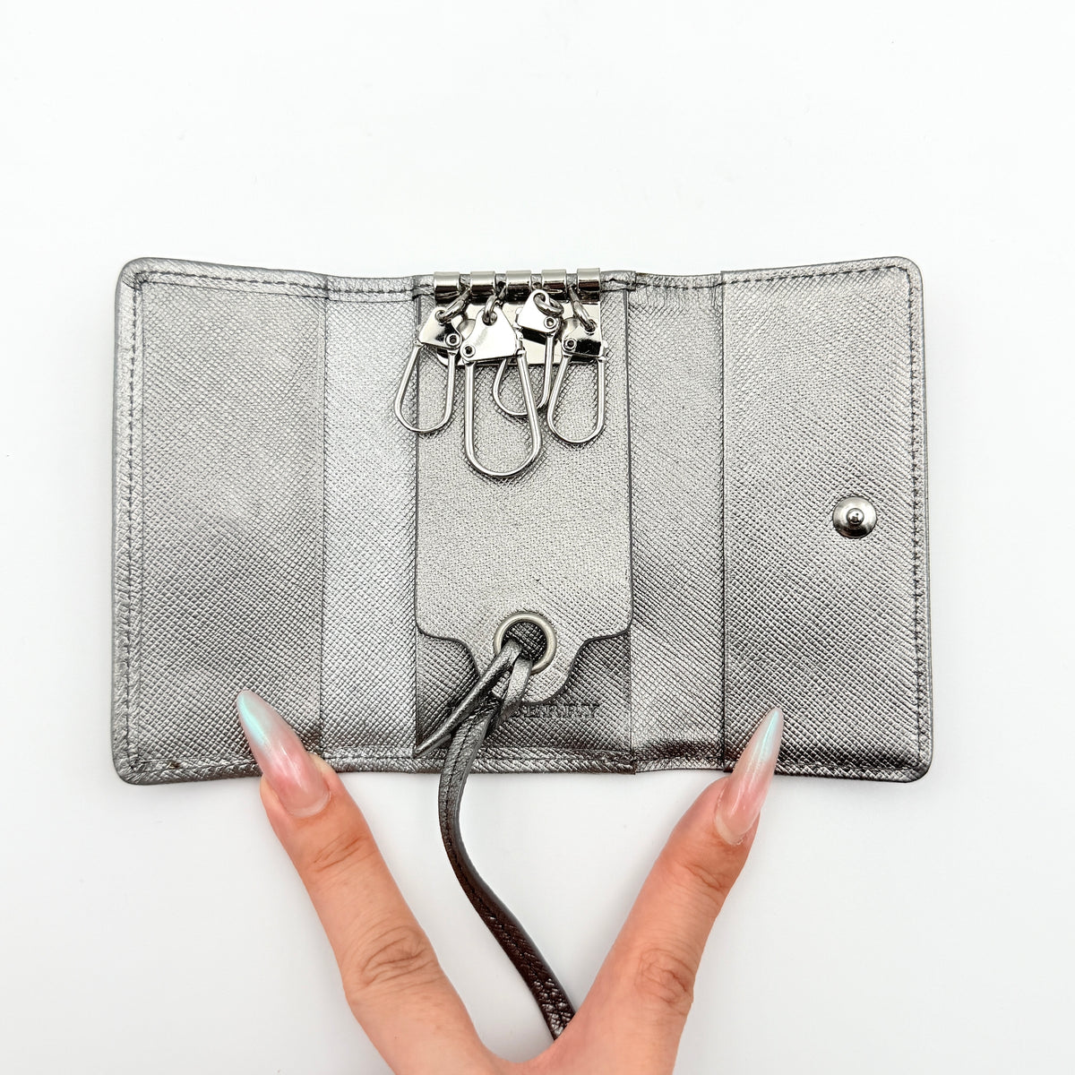 Burberry Nova Check key case in metallic silver leather and beige check canvas with key ring and snap closure.