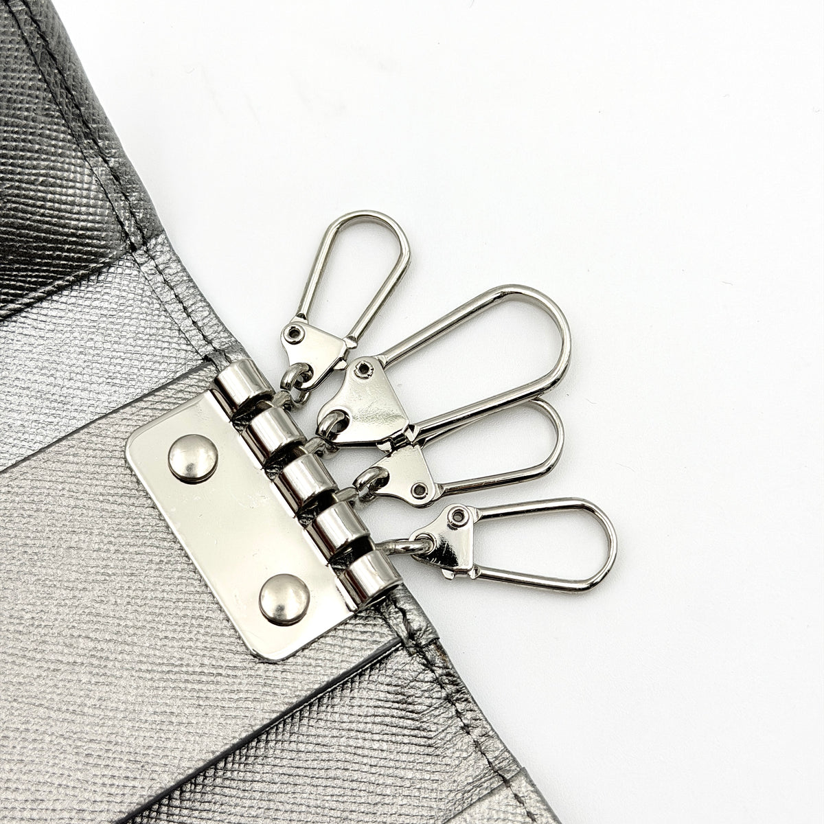 Burberry Nova Check key case in metallic silver leather and beige check canvas with key ring and snap closure.