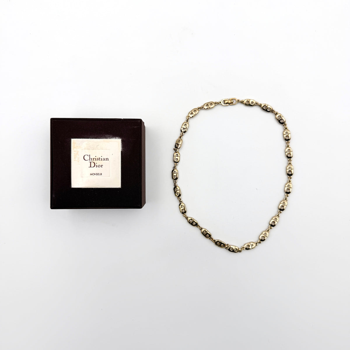 Christian Dior gold CD logo link choker necklace displayed on its original box.