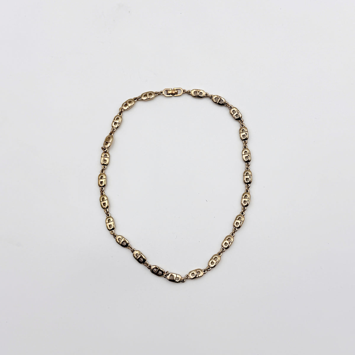 Christian Dior gold CD logo link choker necklace displayed on its original box.