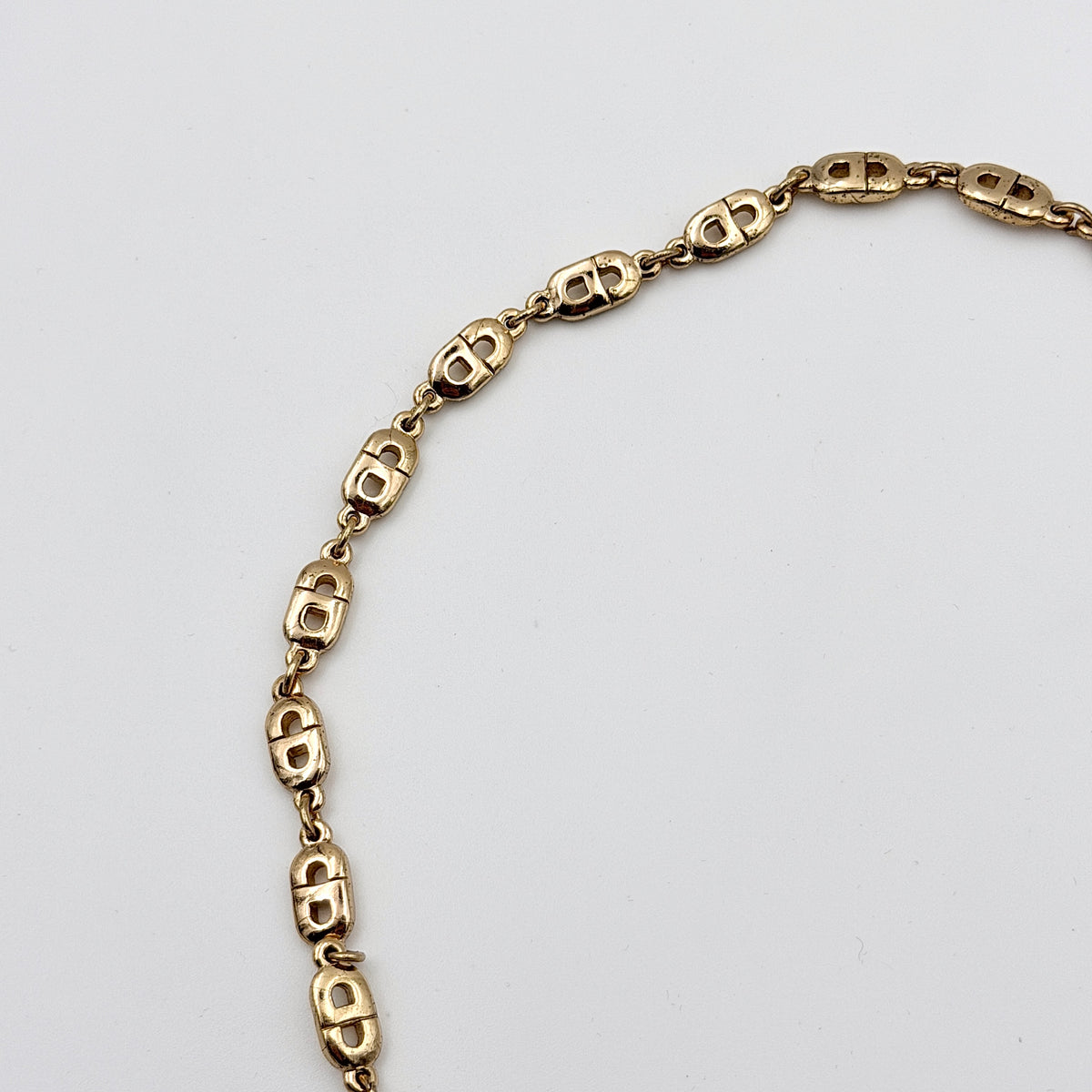 Christian Dior gold CD logo link choker necklace displayed on its original box.