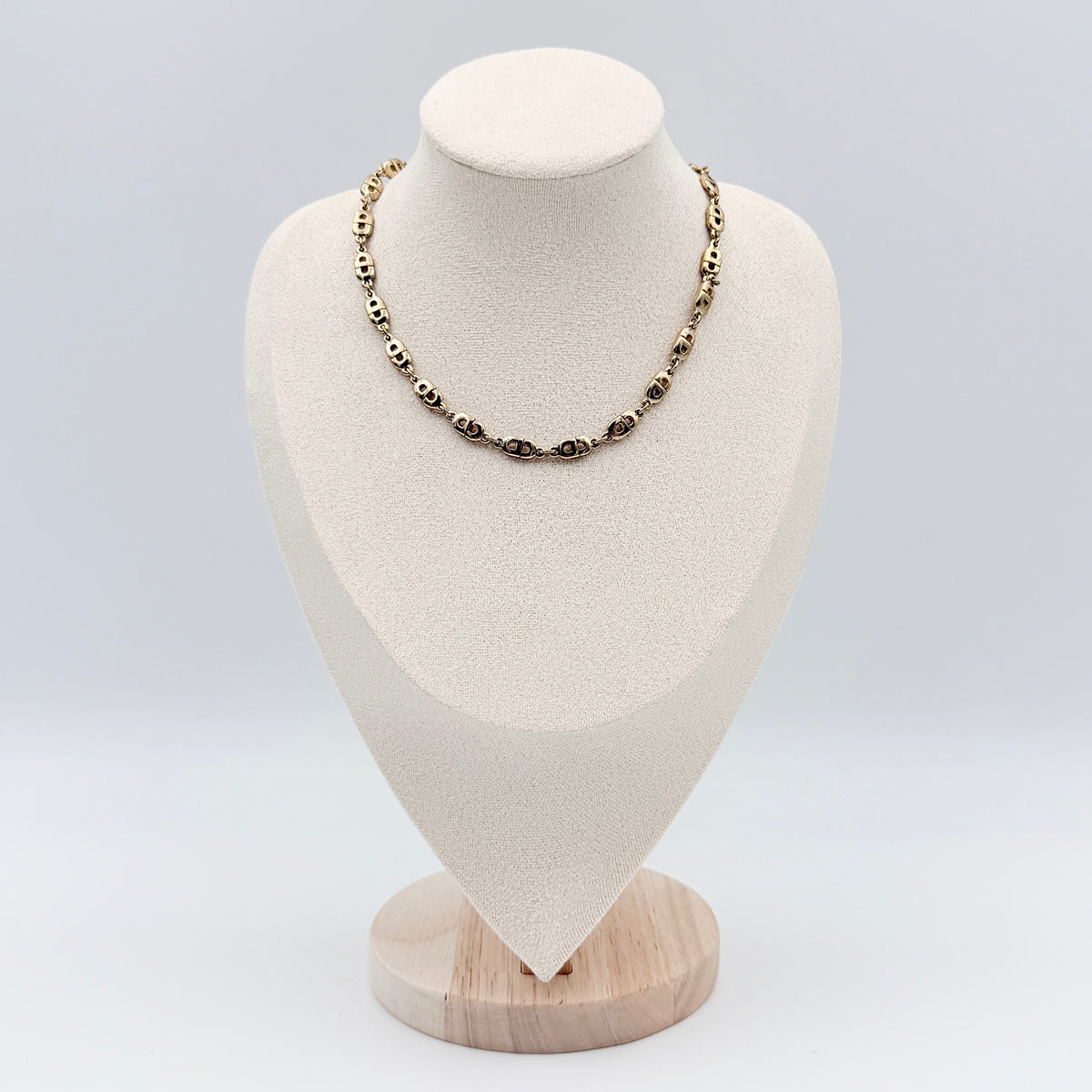 Christian Dior gold CD logo link choker necklace displayed on its original box.