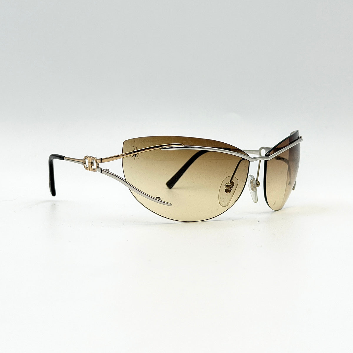 Salvatore Ferragamo rimless sunglasses with gradient brown lenses and sculptural Gancini metal arms on a white background.