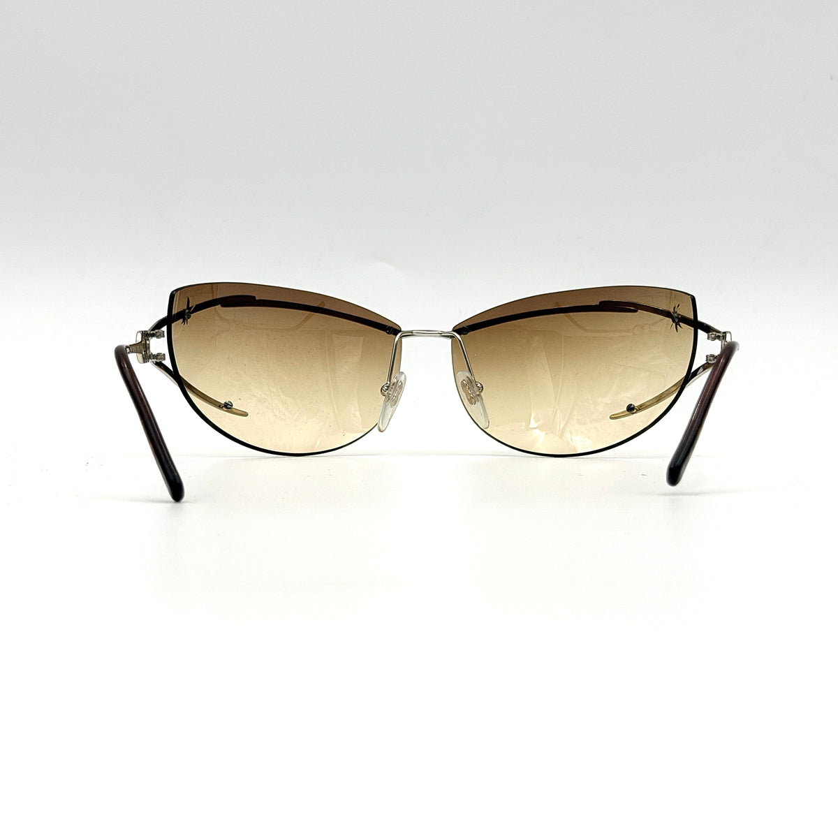 Salvatore Ferragamo rimless sunglasses with gradient brown lenses and sculptural Gancini metal arms on a white background.
