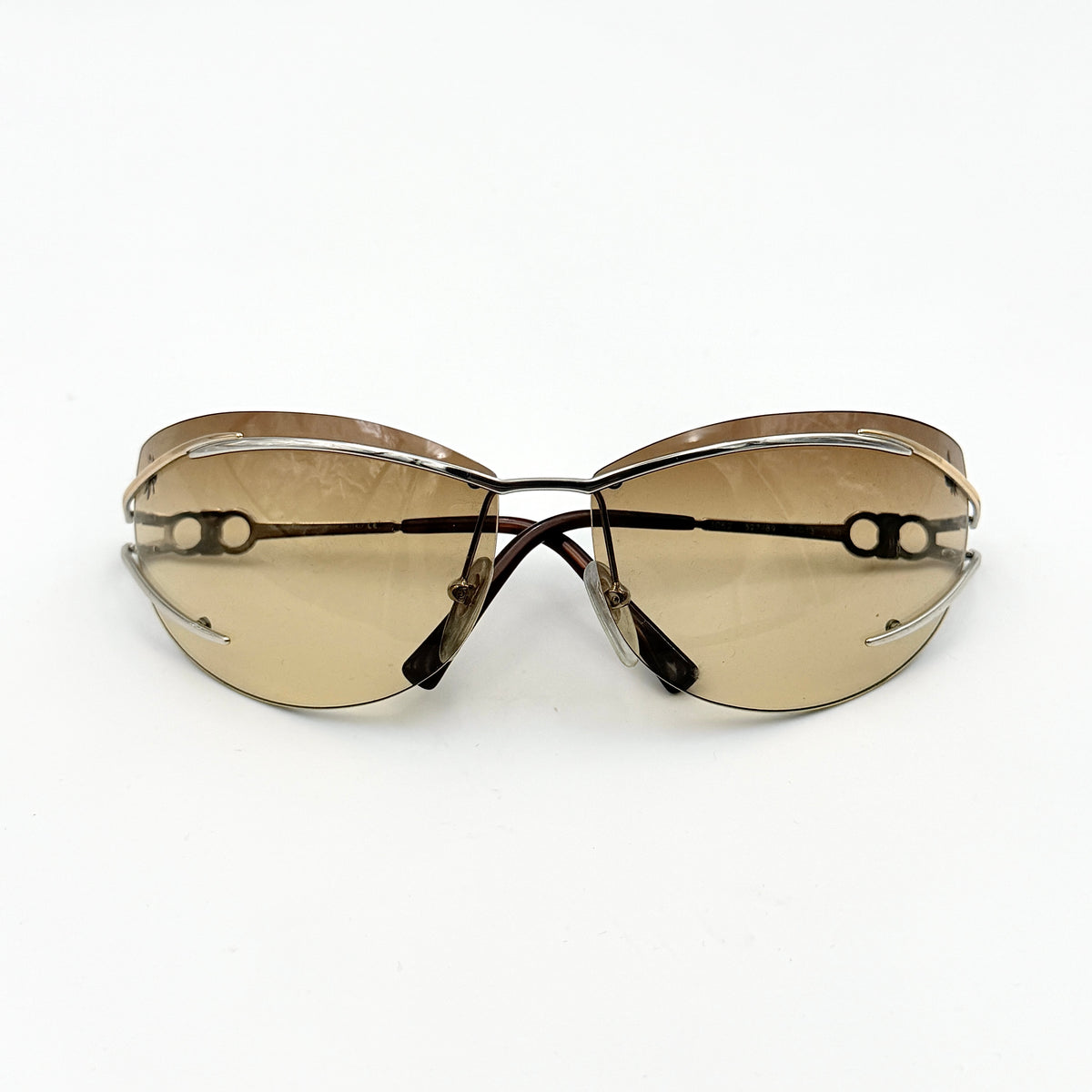 Salvatore Ferragamo rimless sunglasses with gradient brown lenses and sculptural Gancini metal arms on a white background.
