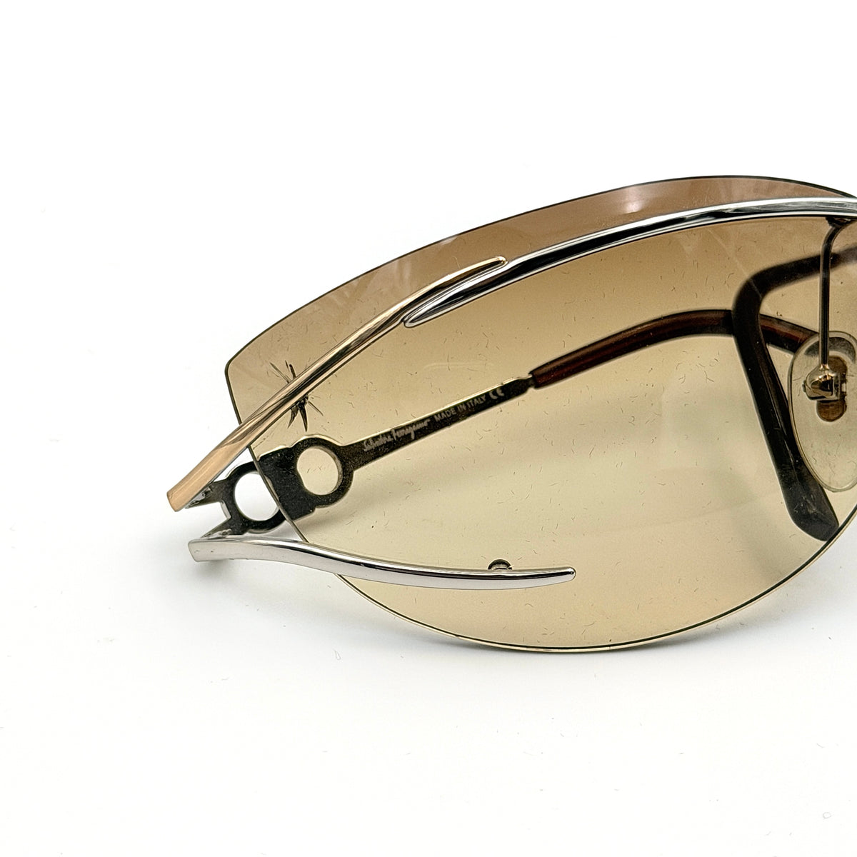Salvatore Ferragamo rimless sunglasses with gradient brown lenses and sculptural Gancini metal arms on a white background.